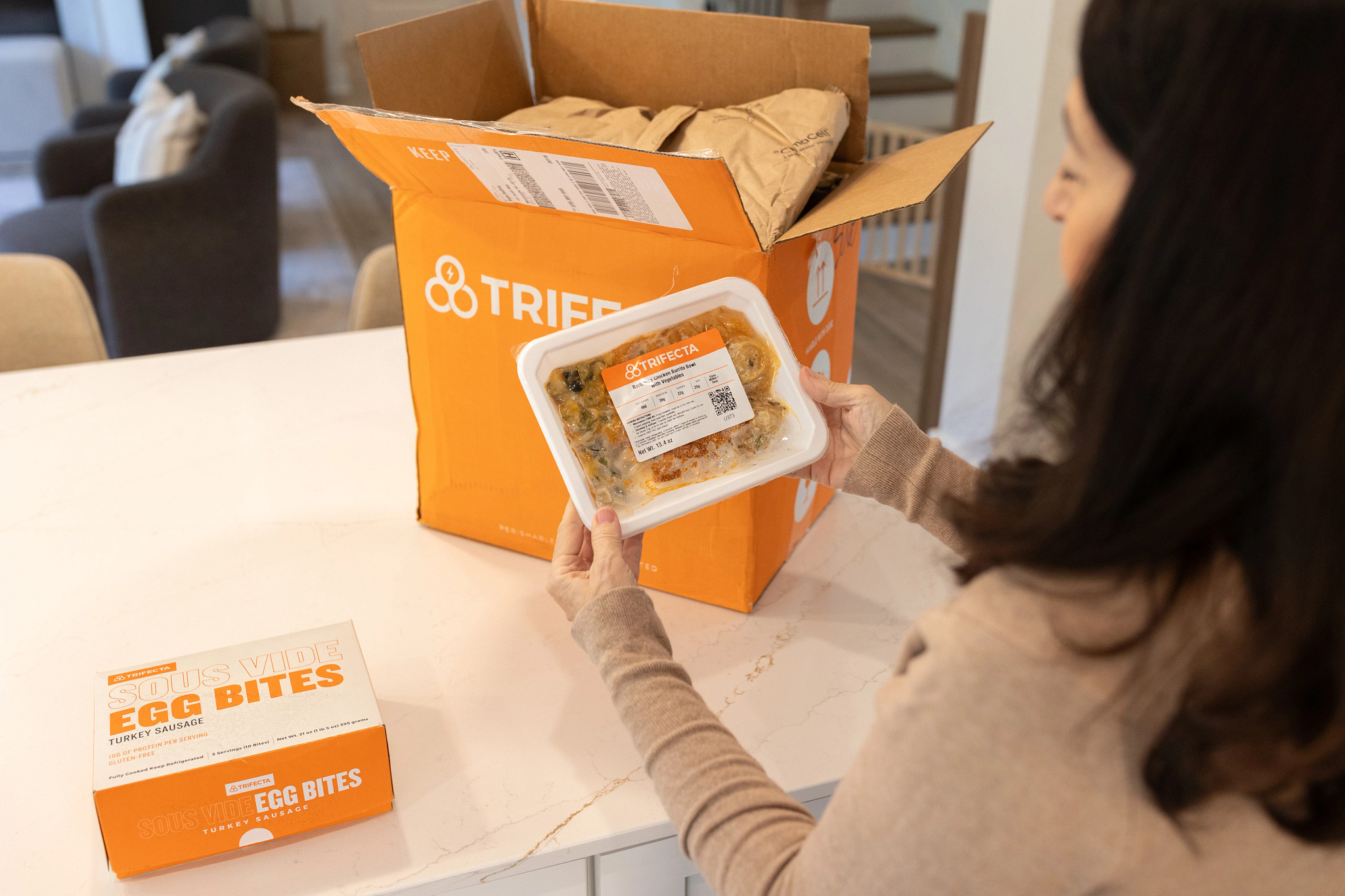 A woman holding a Trifecta prepared meal after taking it out of the box.