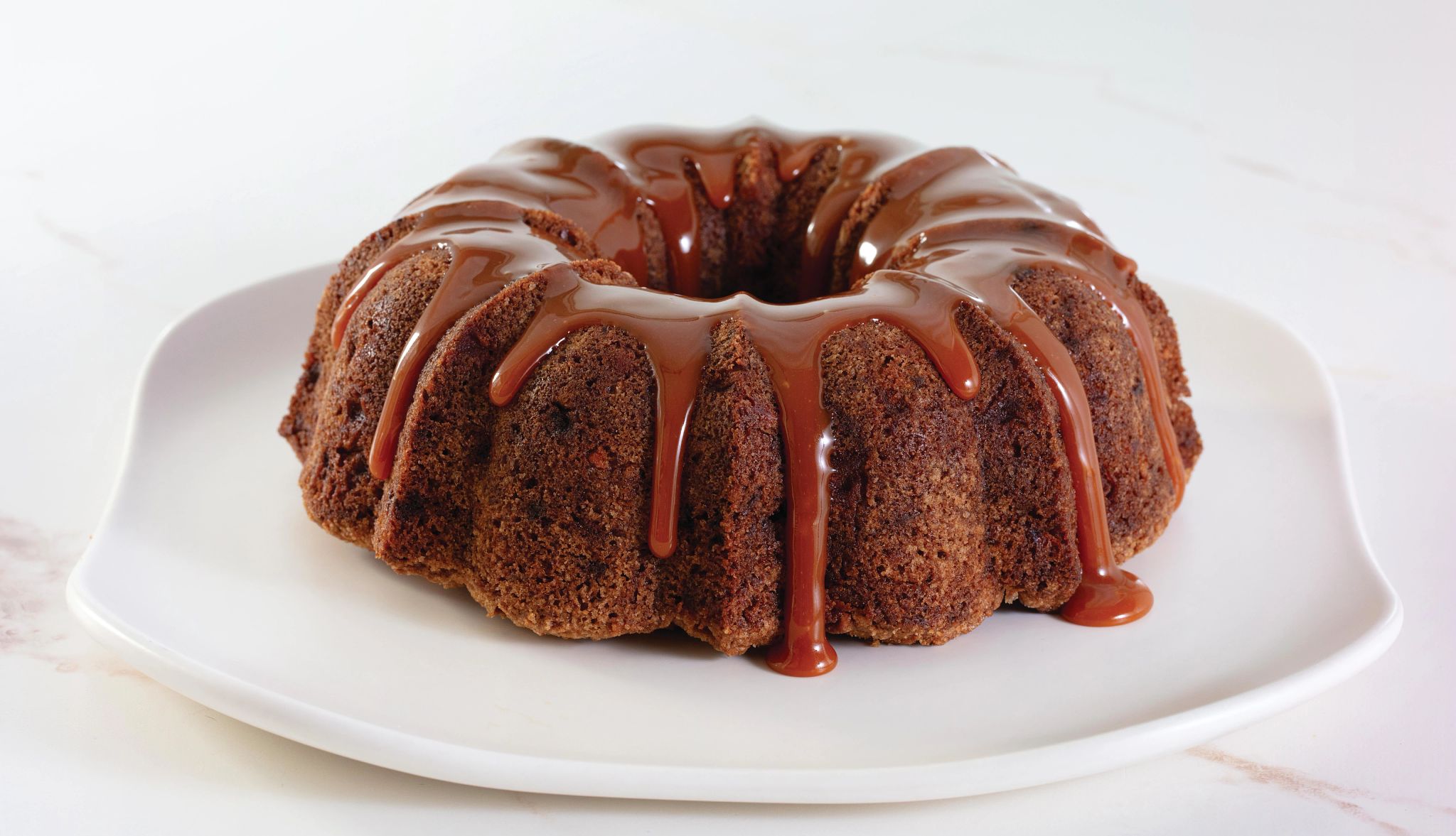 Apple Walnut Bundt Cake Recipe Apple Walnut Bundt Cake with brown glaze dripping down it