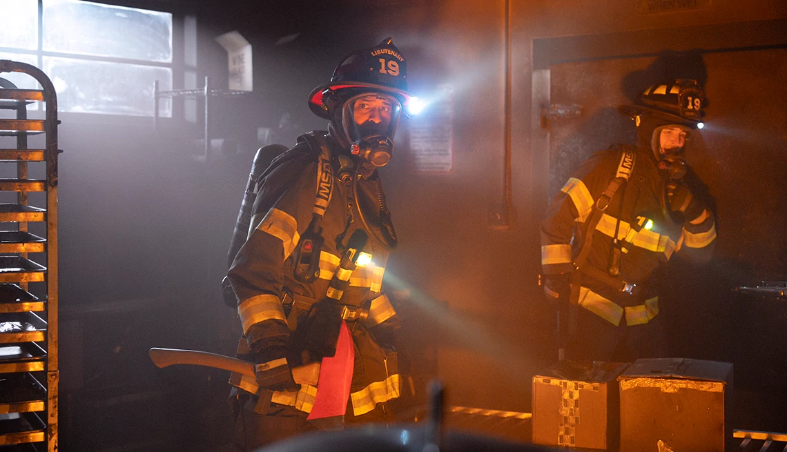 Carlos Miranda and Jay Hayden in firefighting suits in Station 19