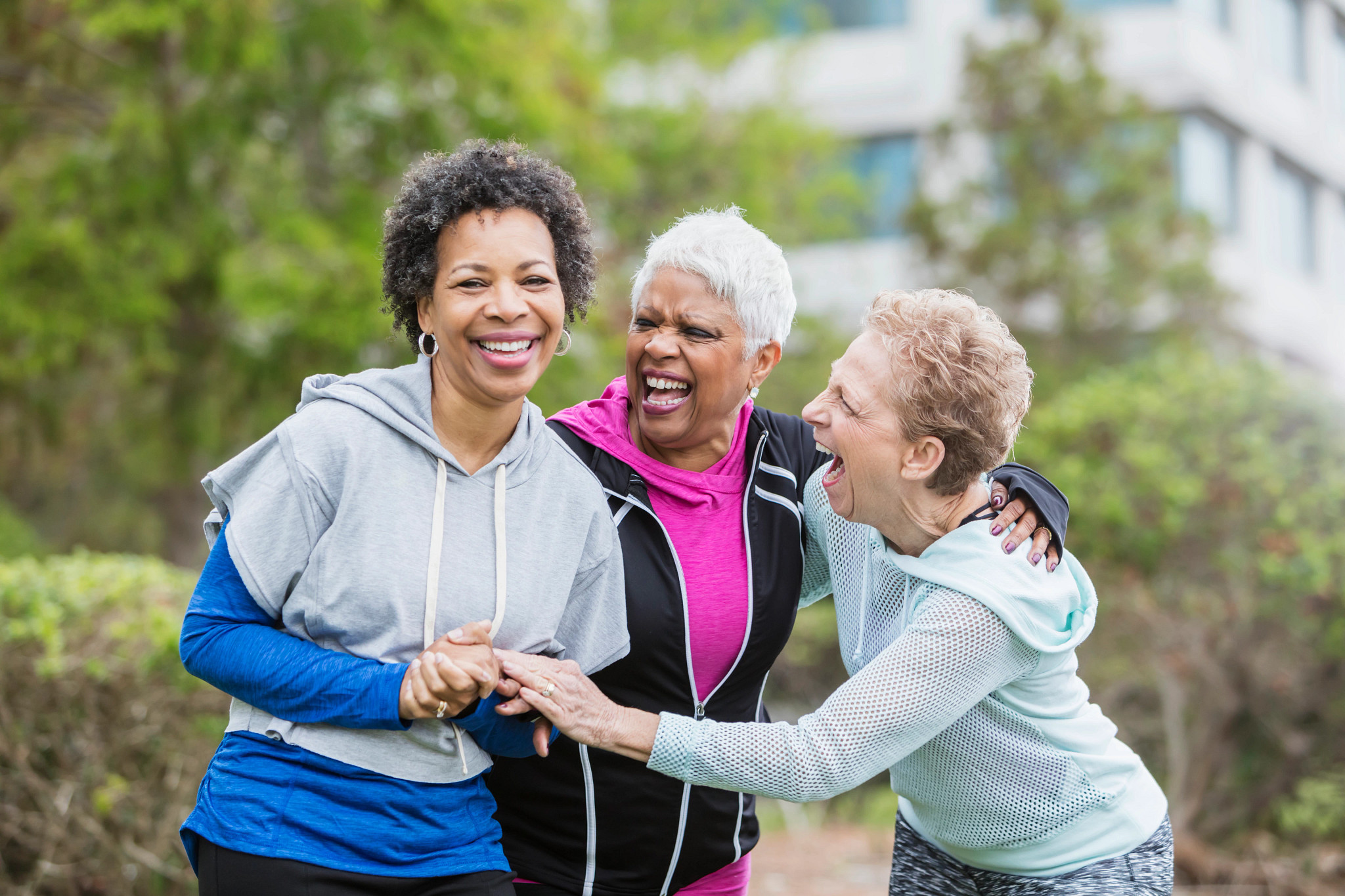 Three smiling women in workout clothing outside