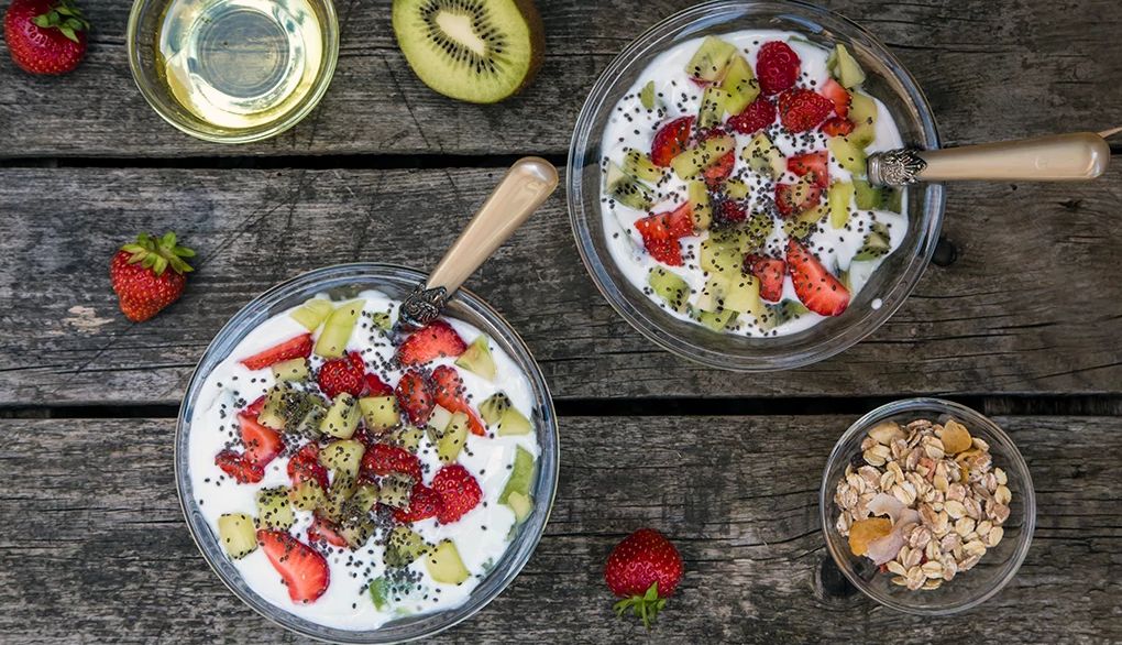 Chia seeds provide healthy nutrients A strawberry kiwi yogurt with cereals, chia seeds and agave syrup in a glass bowl on wood