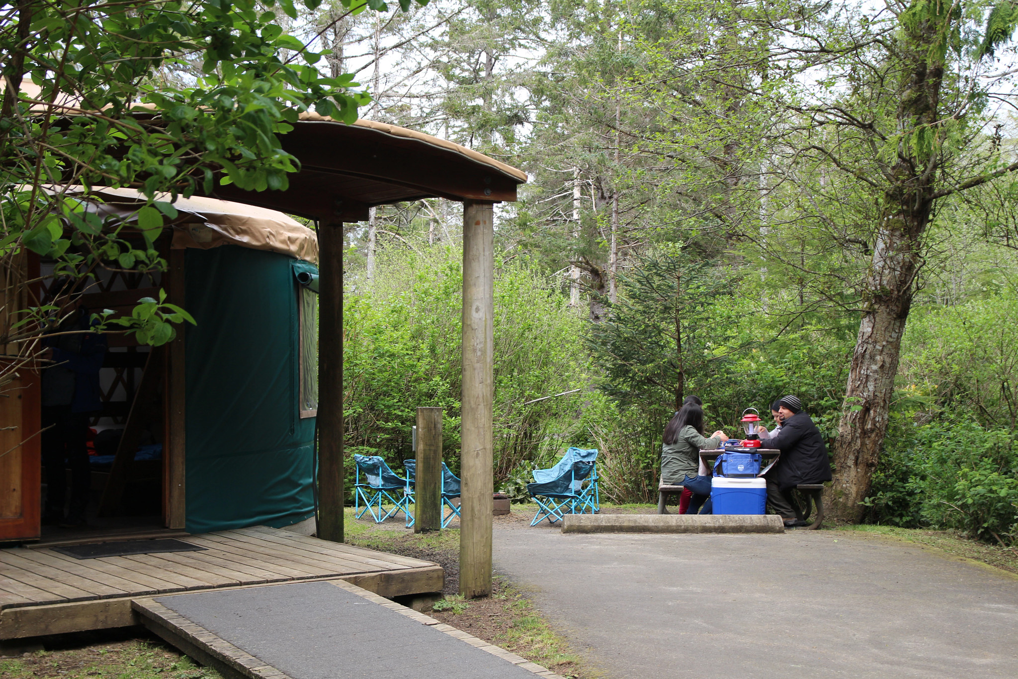 visitors sitting at a picnic table outside a yurt at Cape Lookout State Park campground.