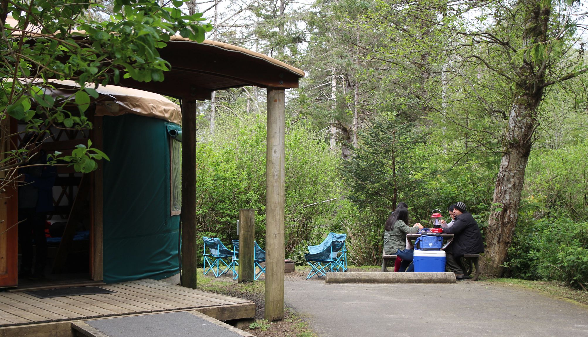 visitantes sentados en una mesa de picnic afuera de una yurta en el campamento del Parque Estatal Cape Lookout.