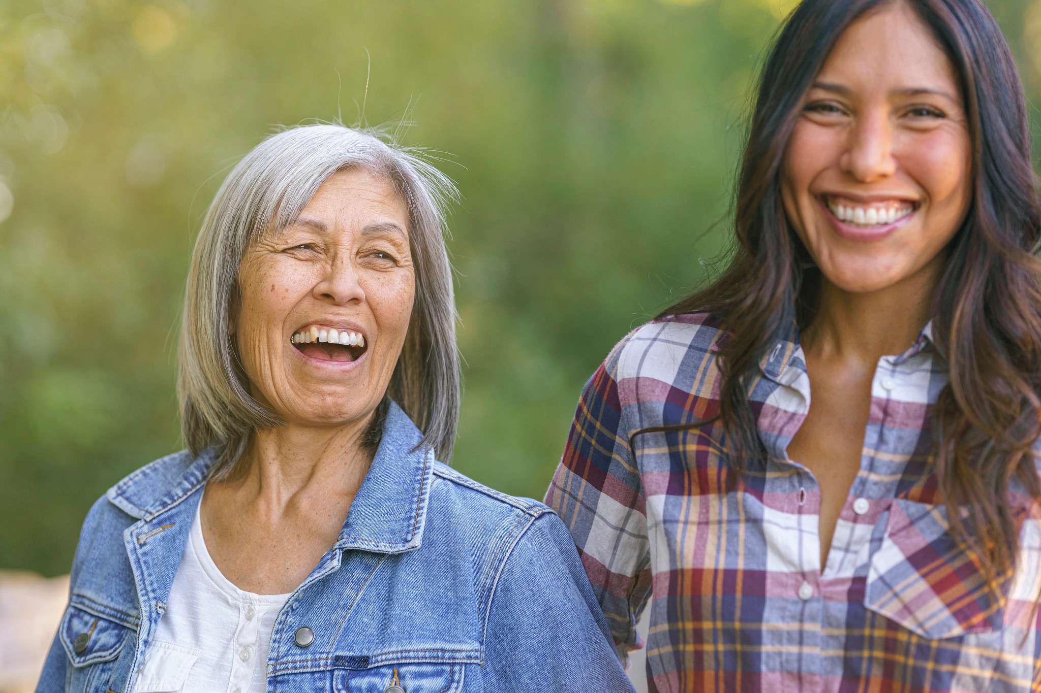 A senior woman laughs while spending time with her adult daughter outdoors