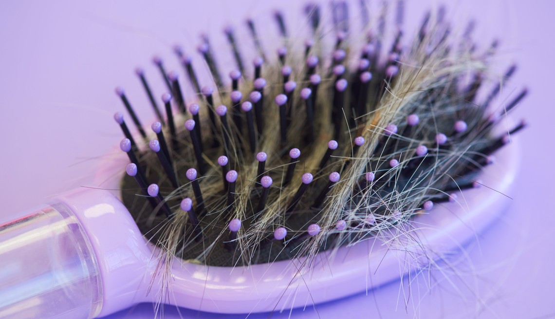 Hair Loss Treatments purple hairbrush with hair