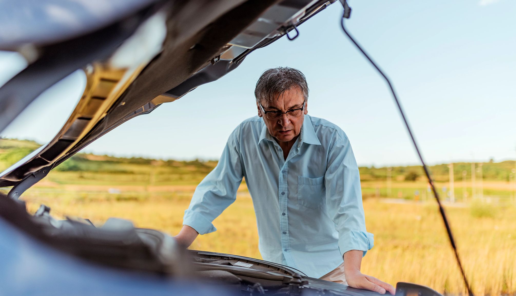 Be sure to get your car checked before heading on a summer road trip stressed man having trouble with his broken car
