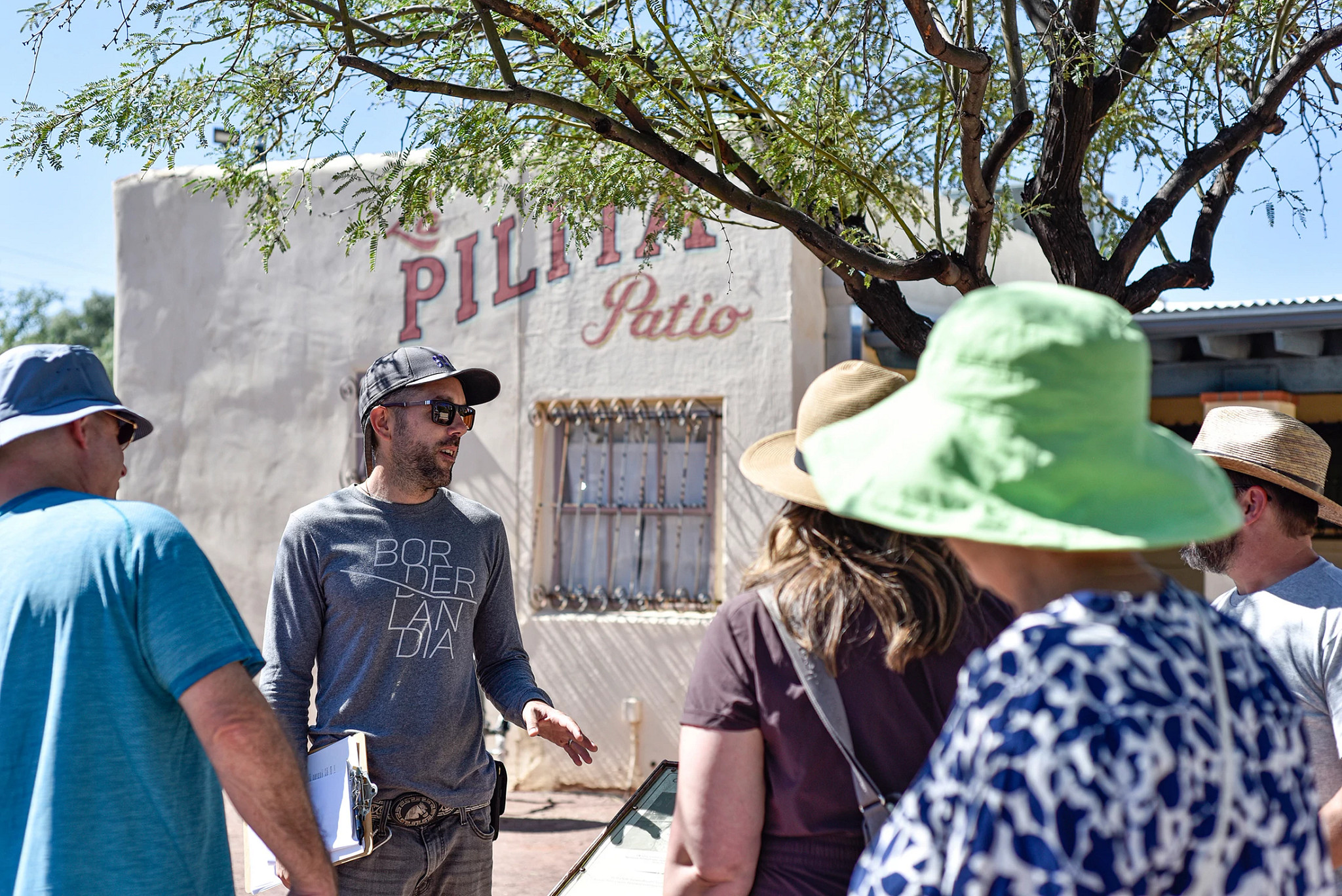 a tour guide speaks to a group standing outside of a building
