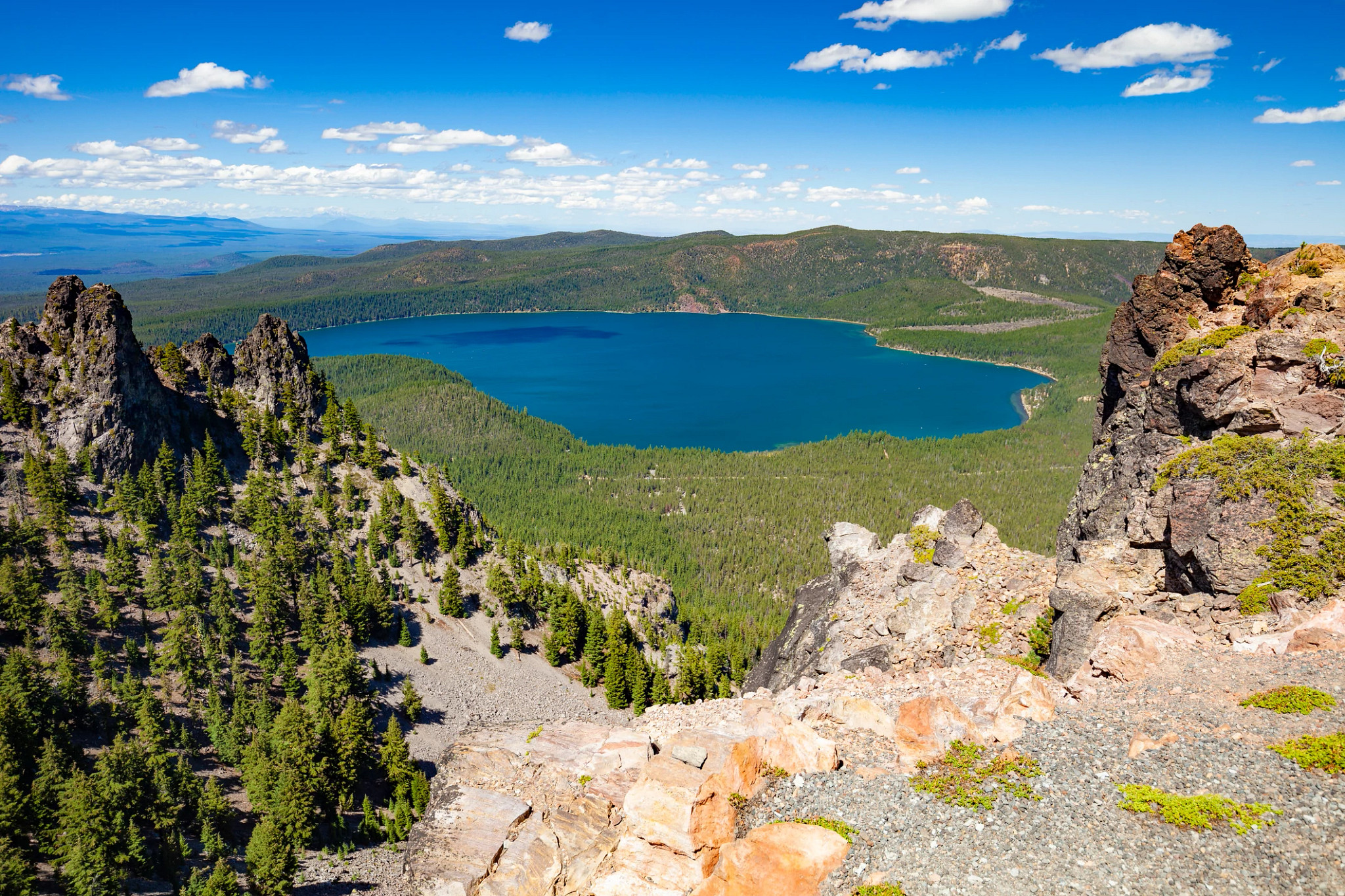 a shot from a mountaintop overlooking a forest and lake