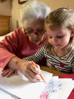 a great grandmother colors with her great granddaughter