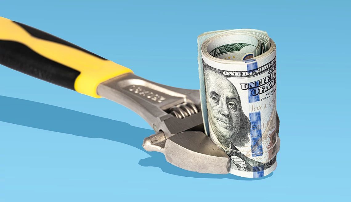 a wrench tightening on a roll of hundred dollar bills