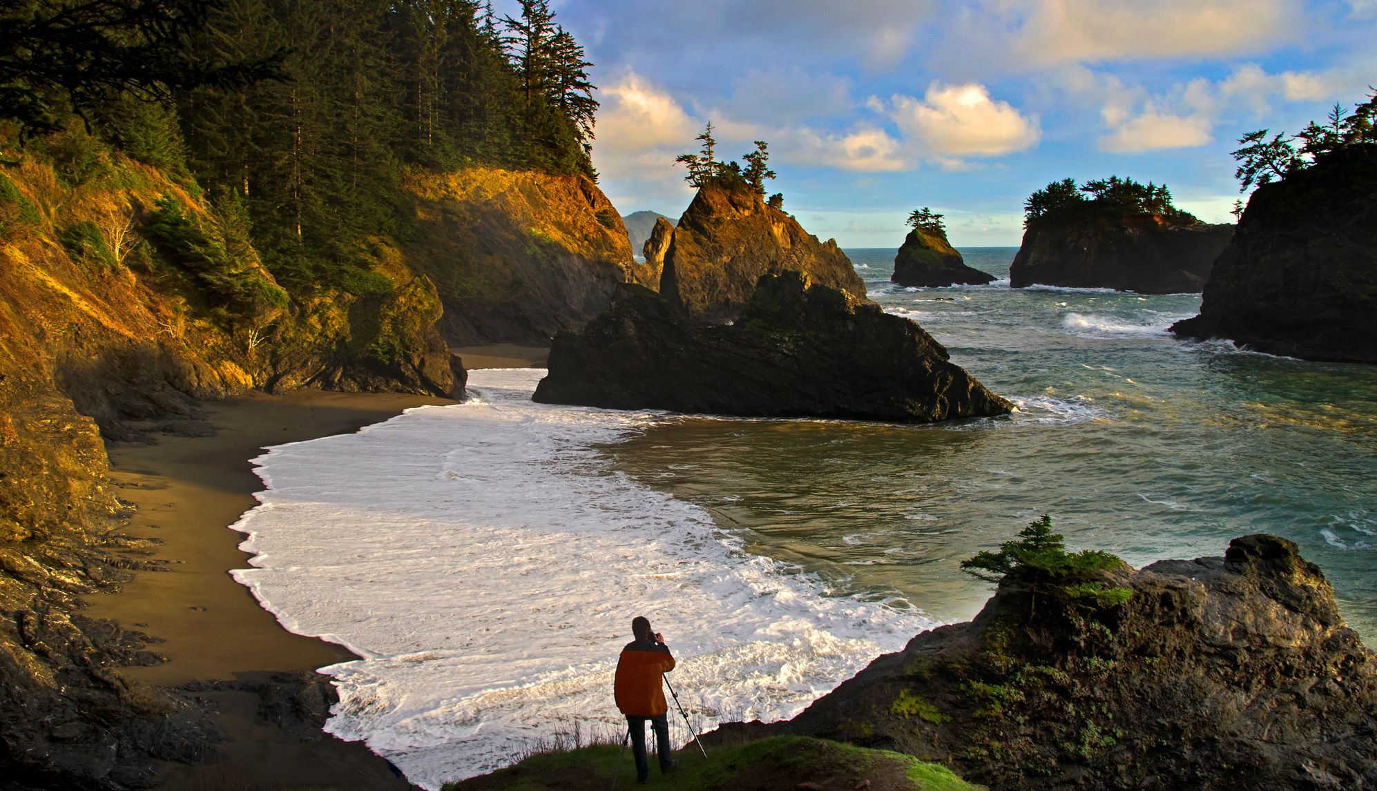 America's Hidden Beaches a person standing on a sea stack overlooking a beach