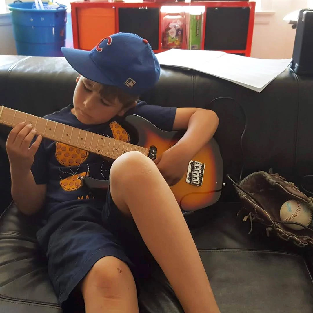 a photo shows author Eric Spitznagel’s son Charlie practicing his guitar as a child