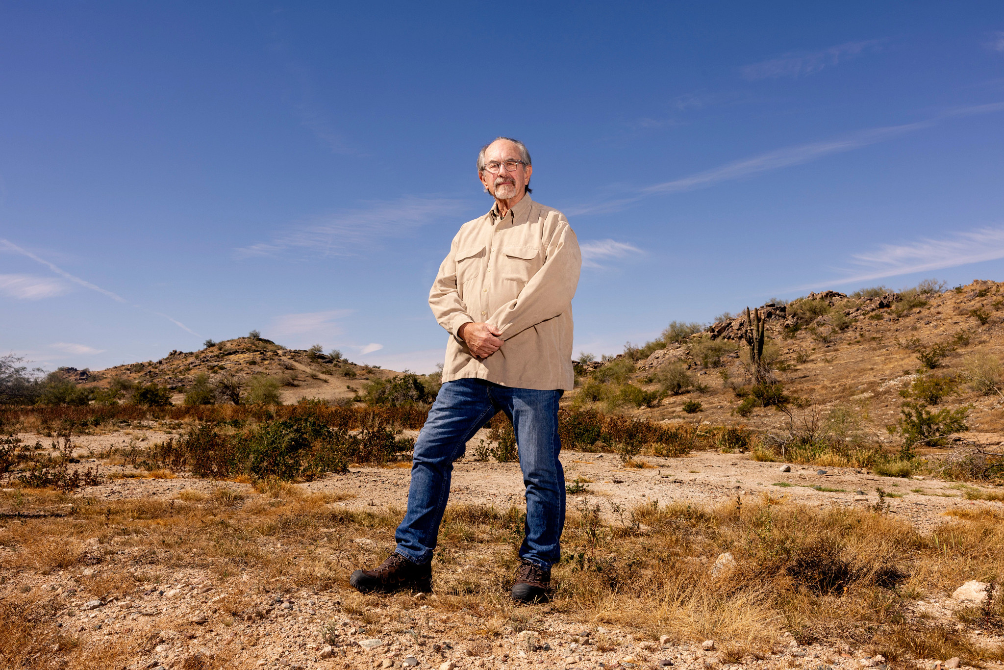a man stands in the desert, looking down at the camera