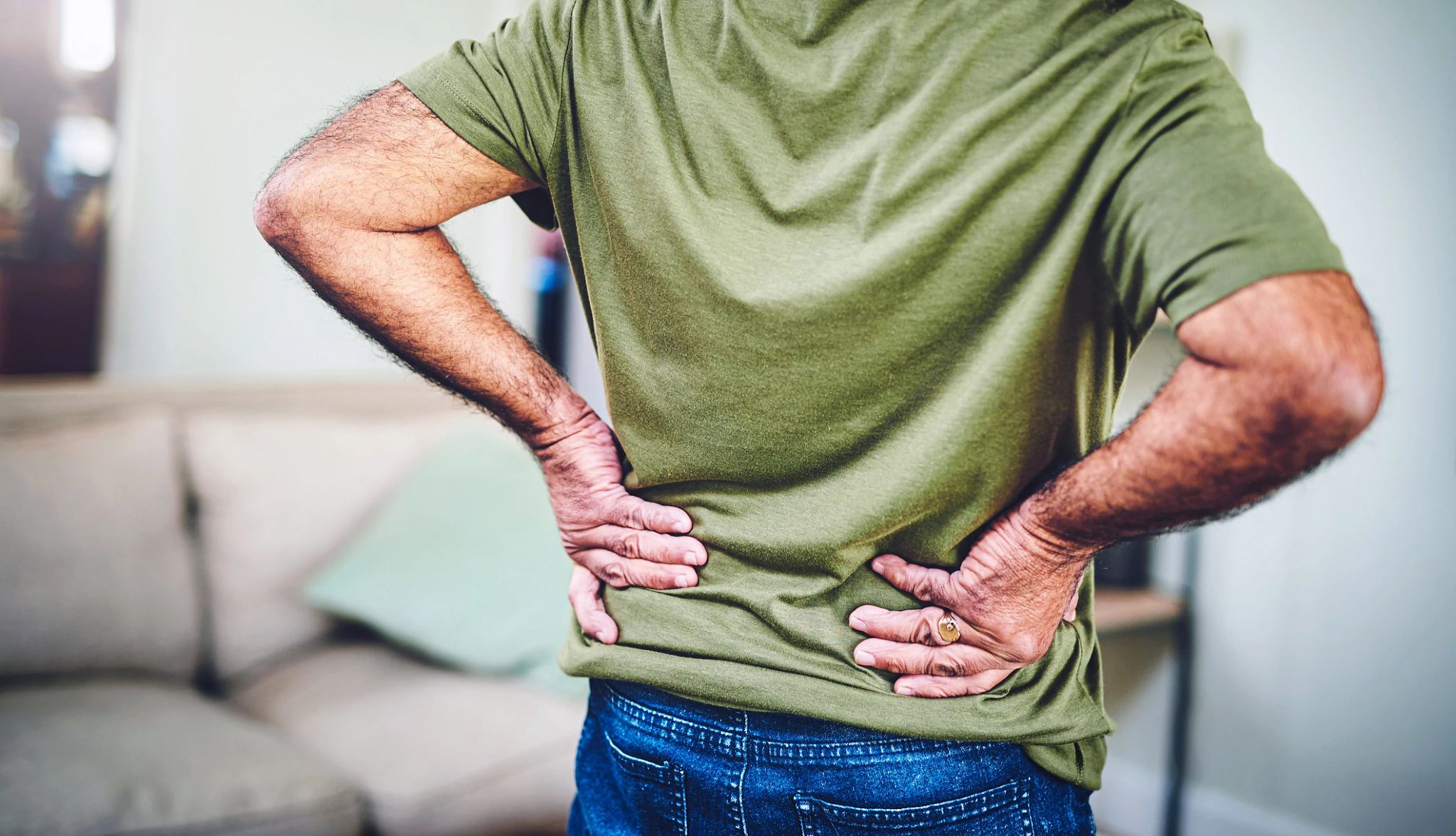 Un hombre se lleva las manos a su espalda baja en señal de dolor