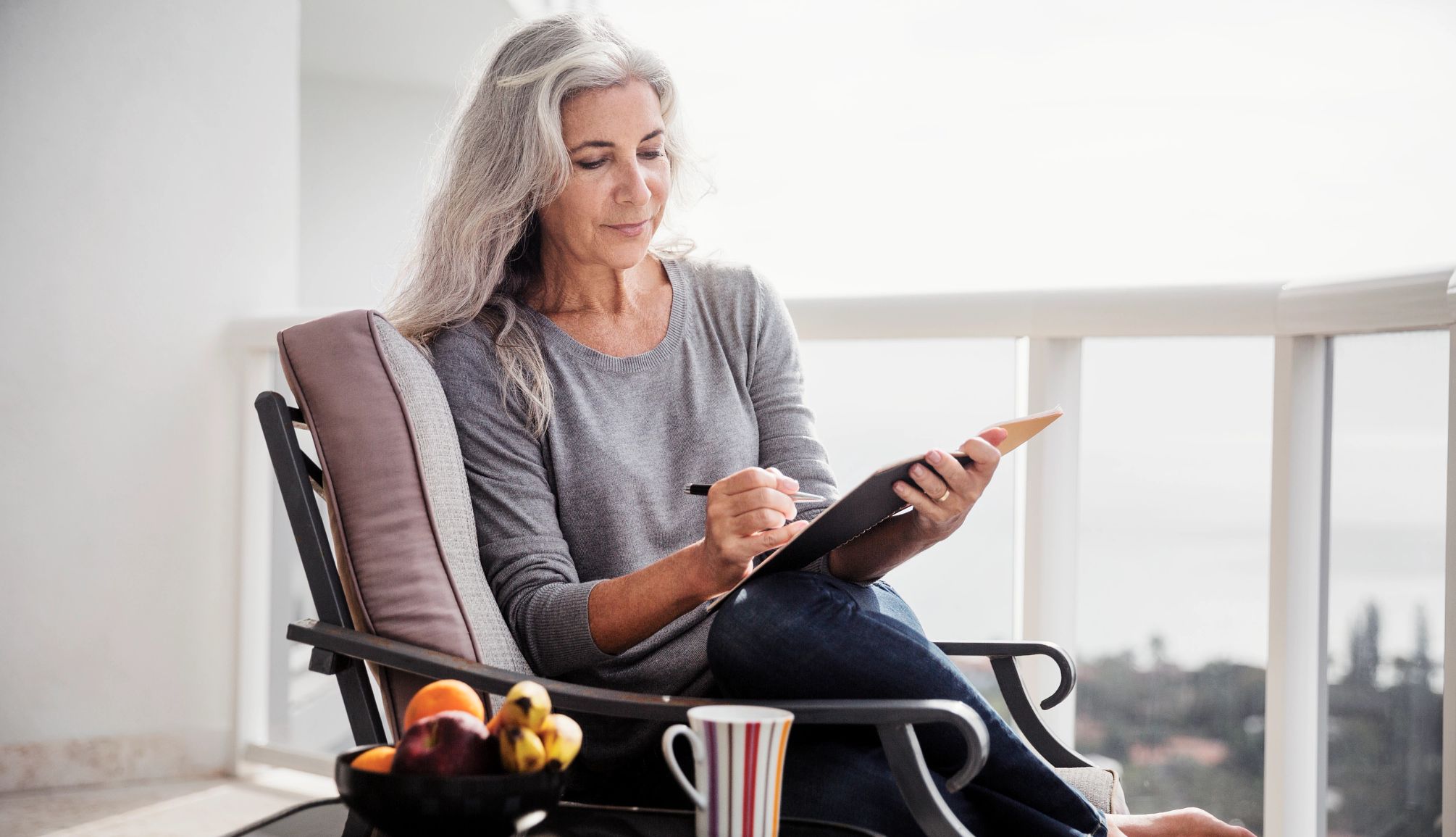 write down your bucket list destinations woman sitting on a couch writing in a notebook