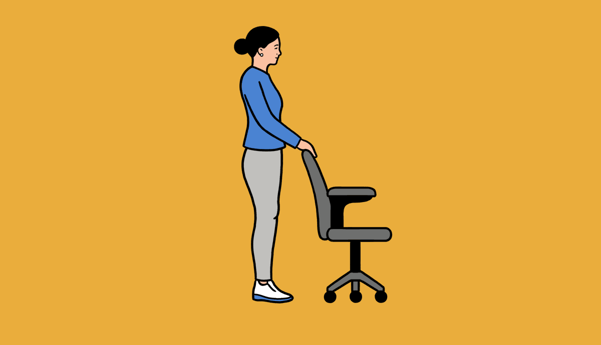A woman stands behind a desk chair, holding onto the chair while pushing up on her toes.