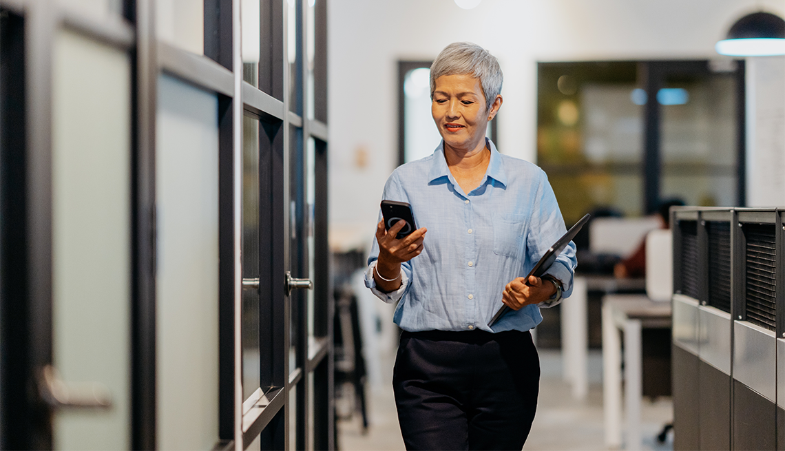 Taking advantage of technology may help you manage brain fog at work A woman looking at her smartphone while walking in an office