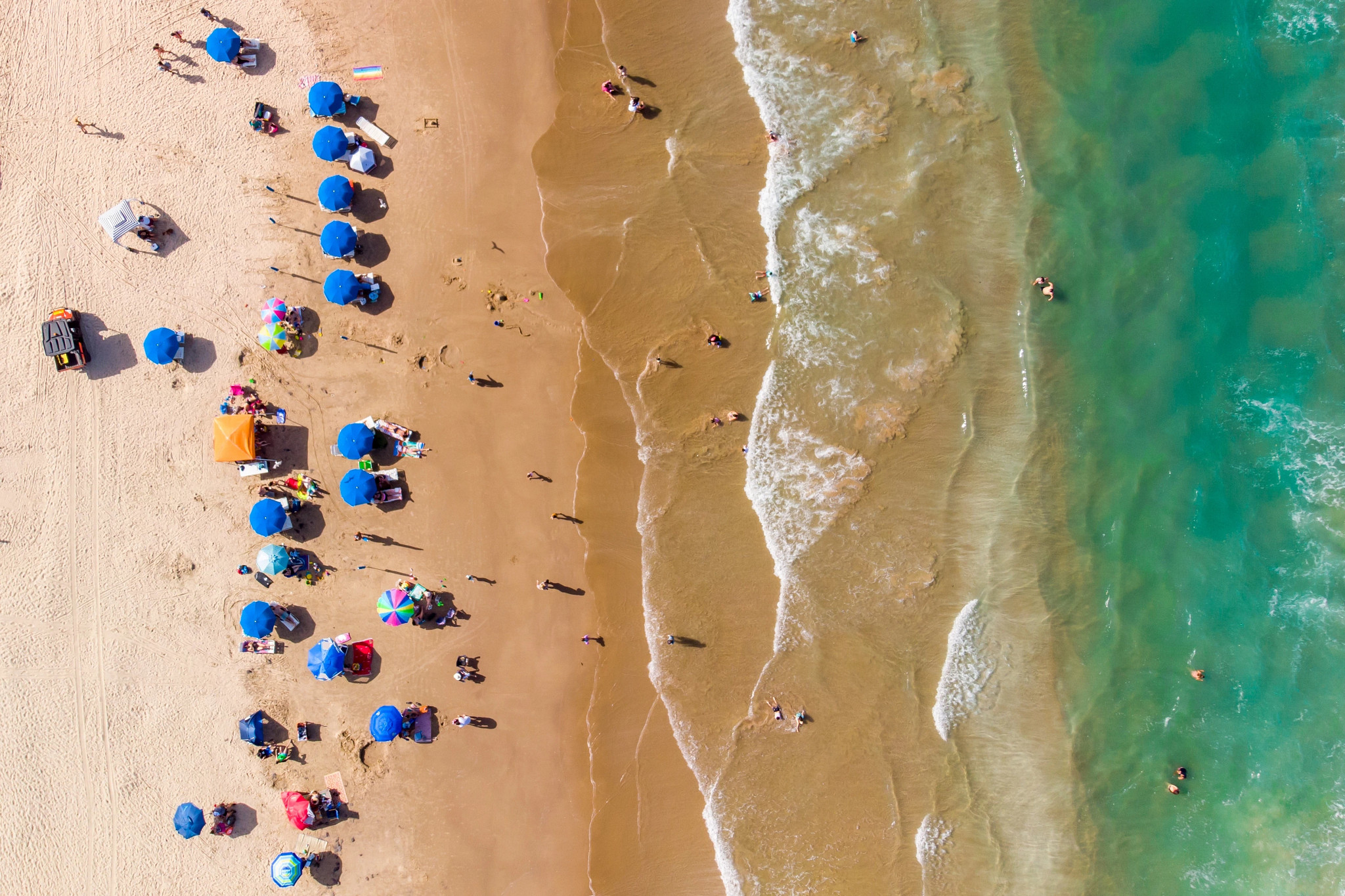 people on the beach with umbrellas and towels
