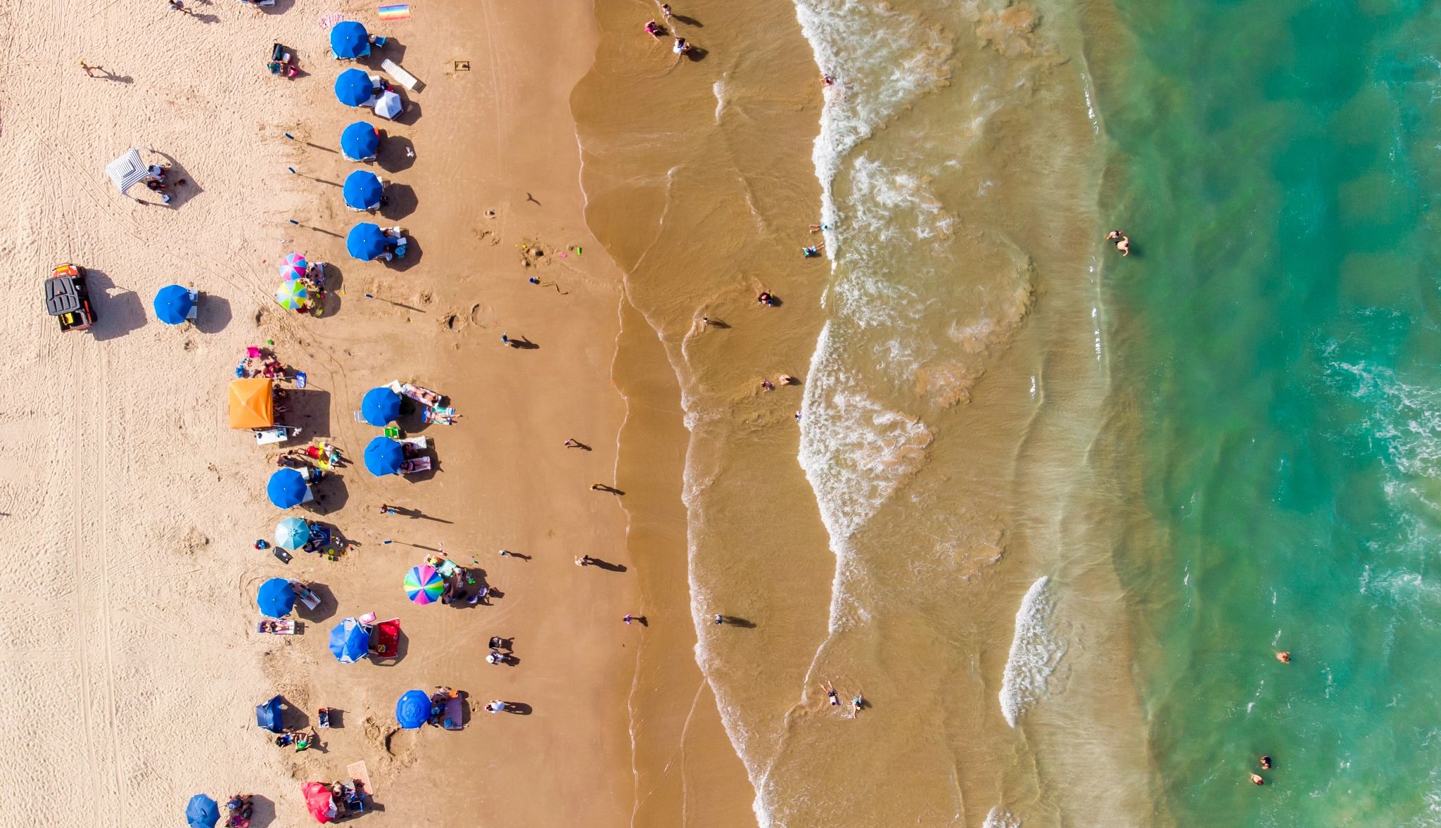 Beach Towns for Fall Getaways people on the beach with umbrellas and towels