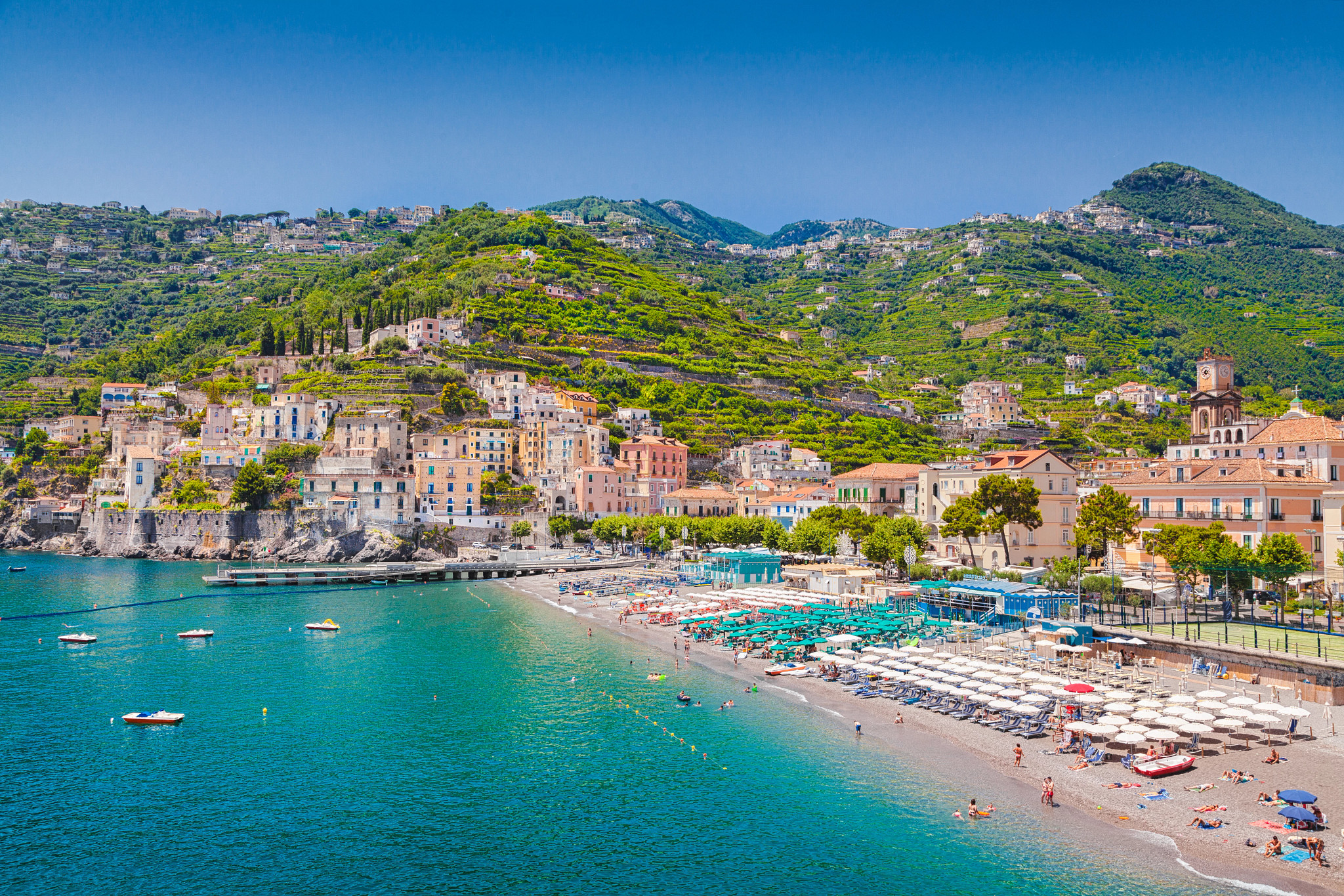 Scenic Amalfi Coast beach with turquoise water, colorful hillside homes and coastal mountains in Italy.