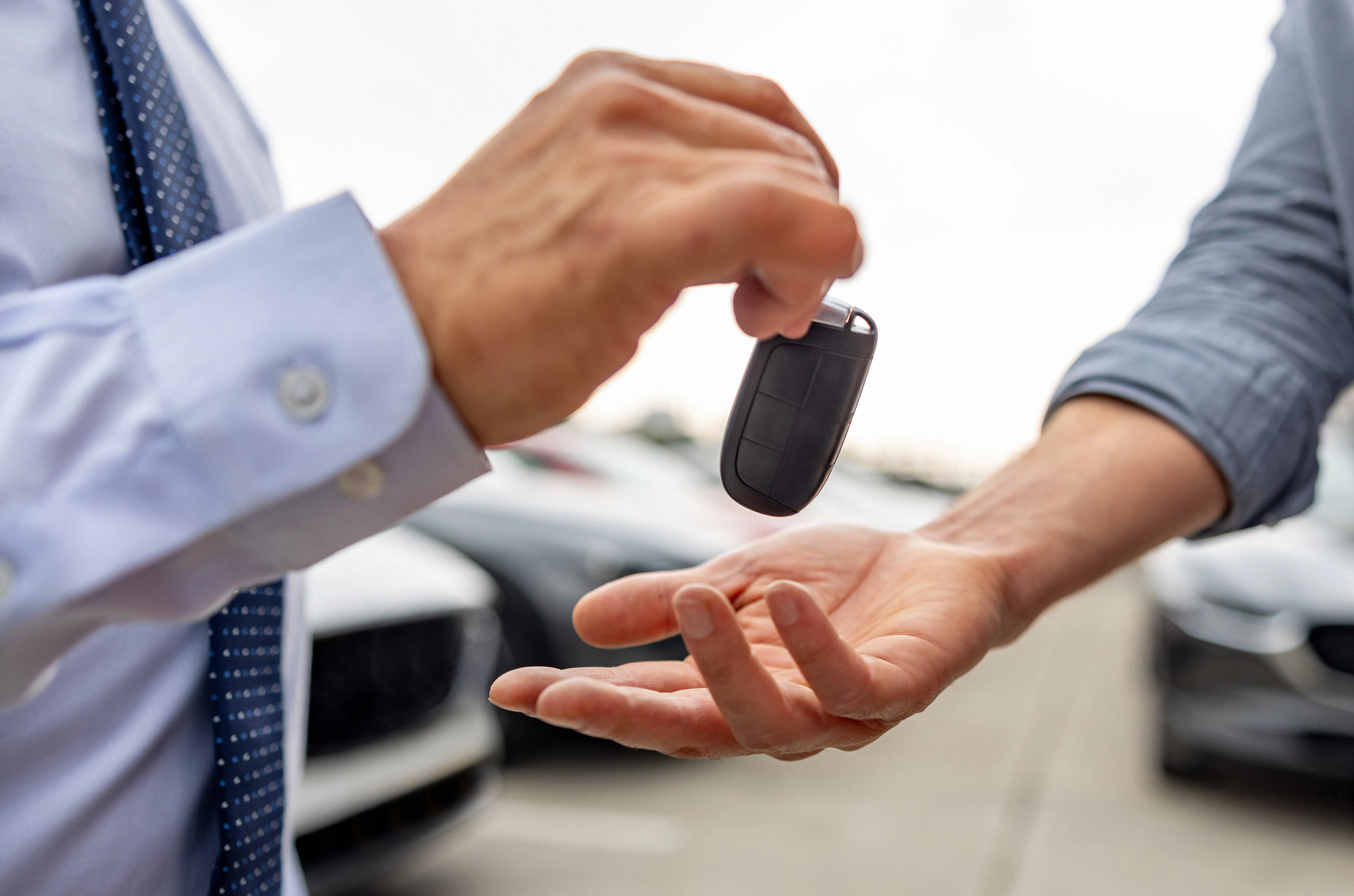 a photo shows a man handing another man a car fob