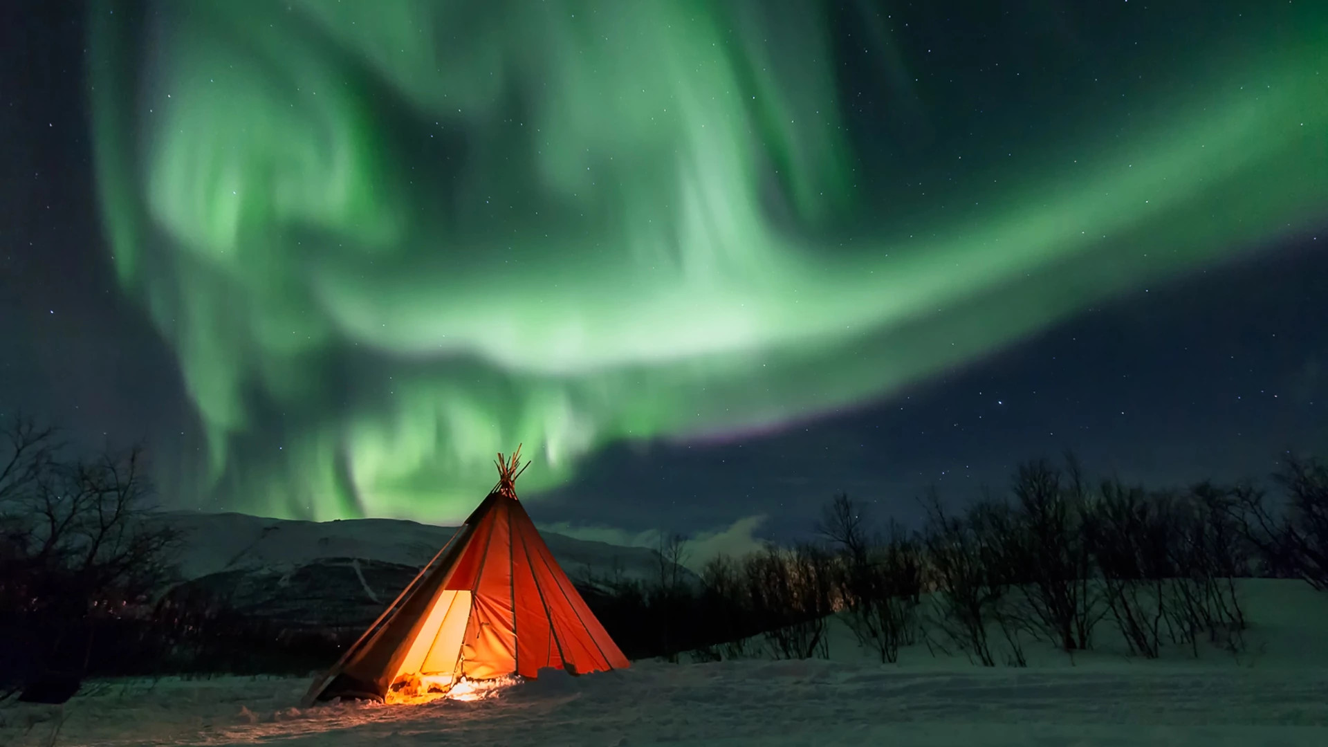 a tent lit up at night with the Northern Lights in the sky