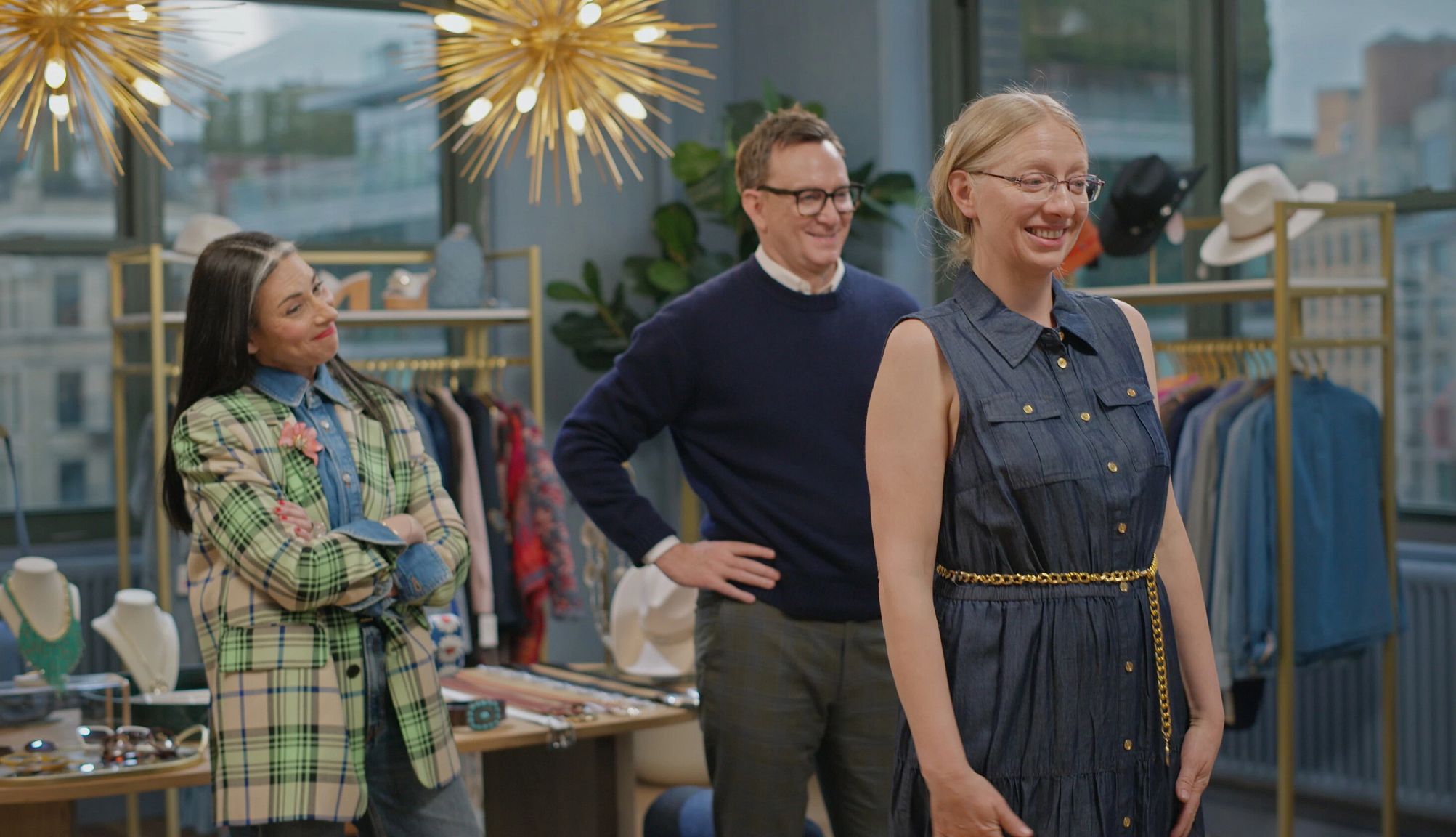 Stacy London and Clinton Kelly Talk About Their New Show a participant smiling while trying on an outfit as stacy london and clinton kelly look on