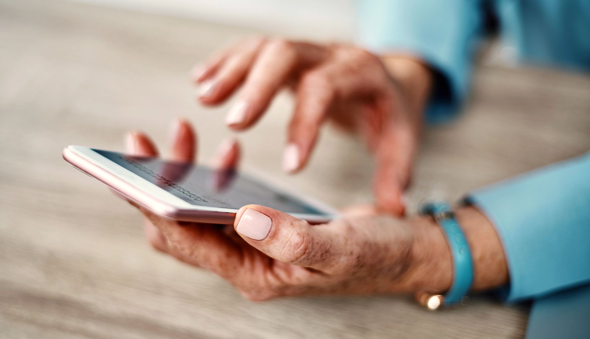 Se ven las manos de una mujer mayor marcando un número en un celular.