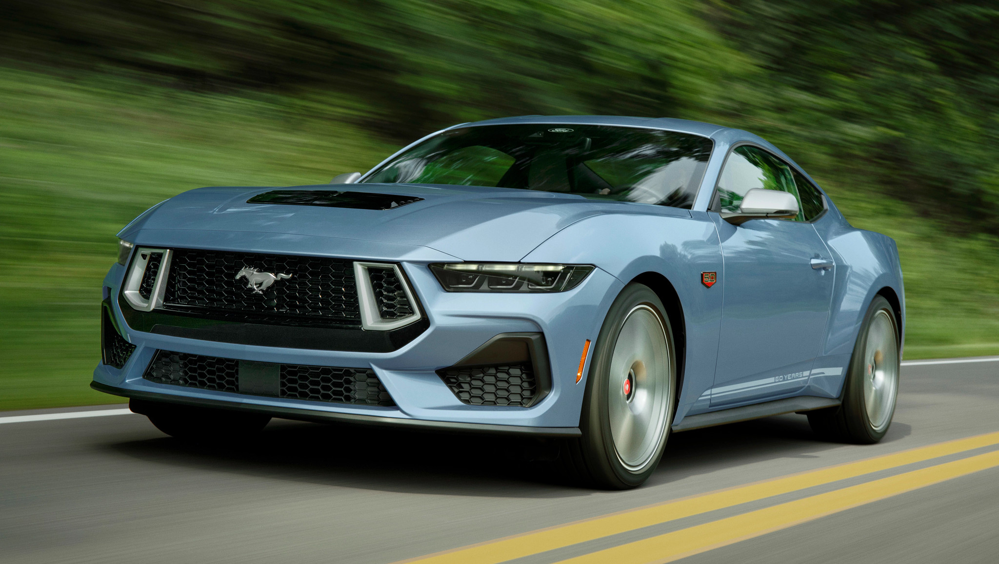 a blue sports car drives on a road