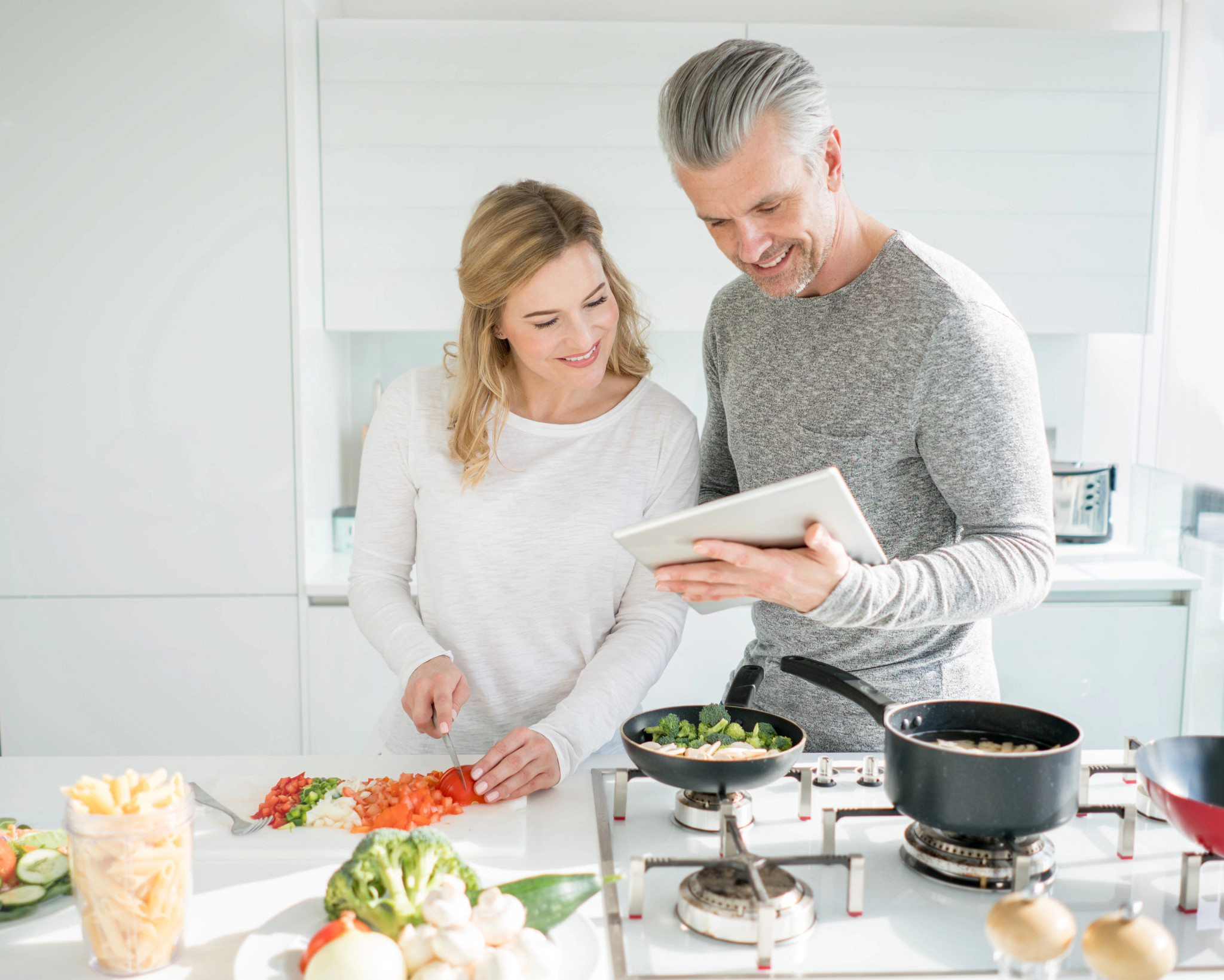 Loving couple cooking dinner together at home and following an online recipe