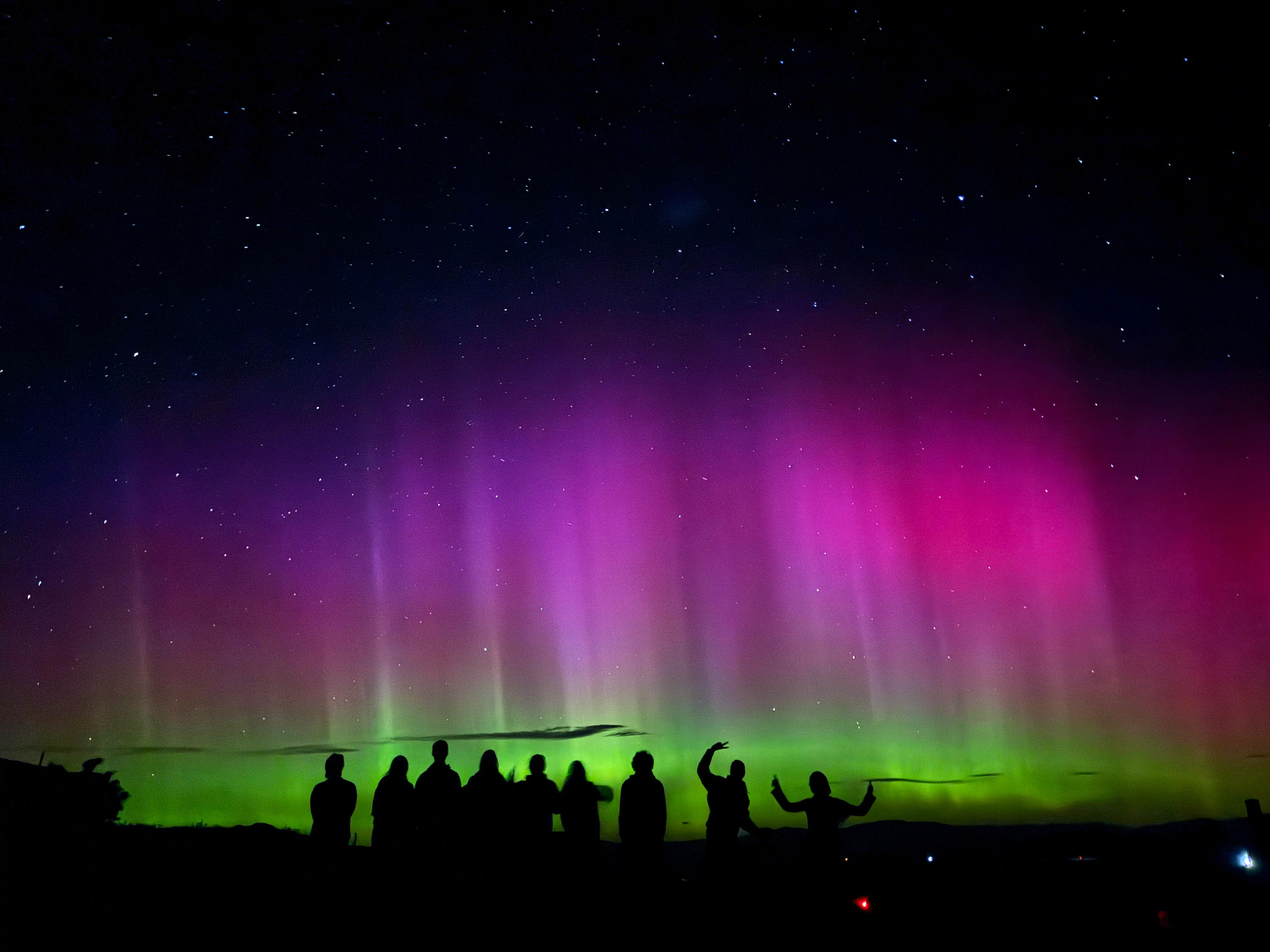people's silhouettes with the southern lights in the background