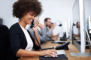 Woman talking on phone while using a computer