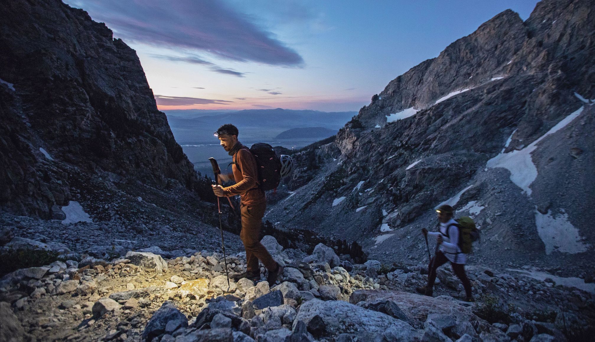 destination that are great for stargazing a man hiking at Grand Teton National Park during dusk