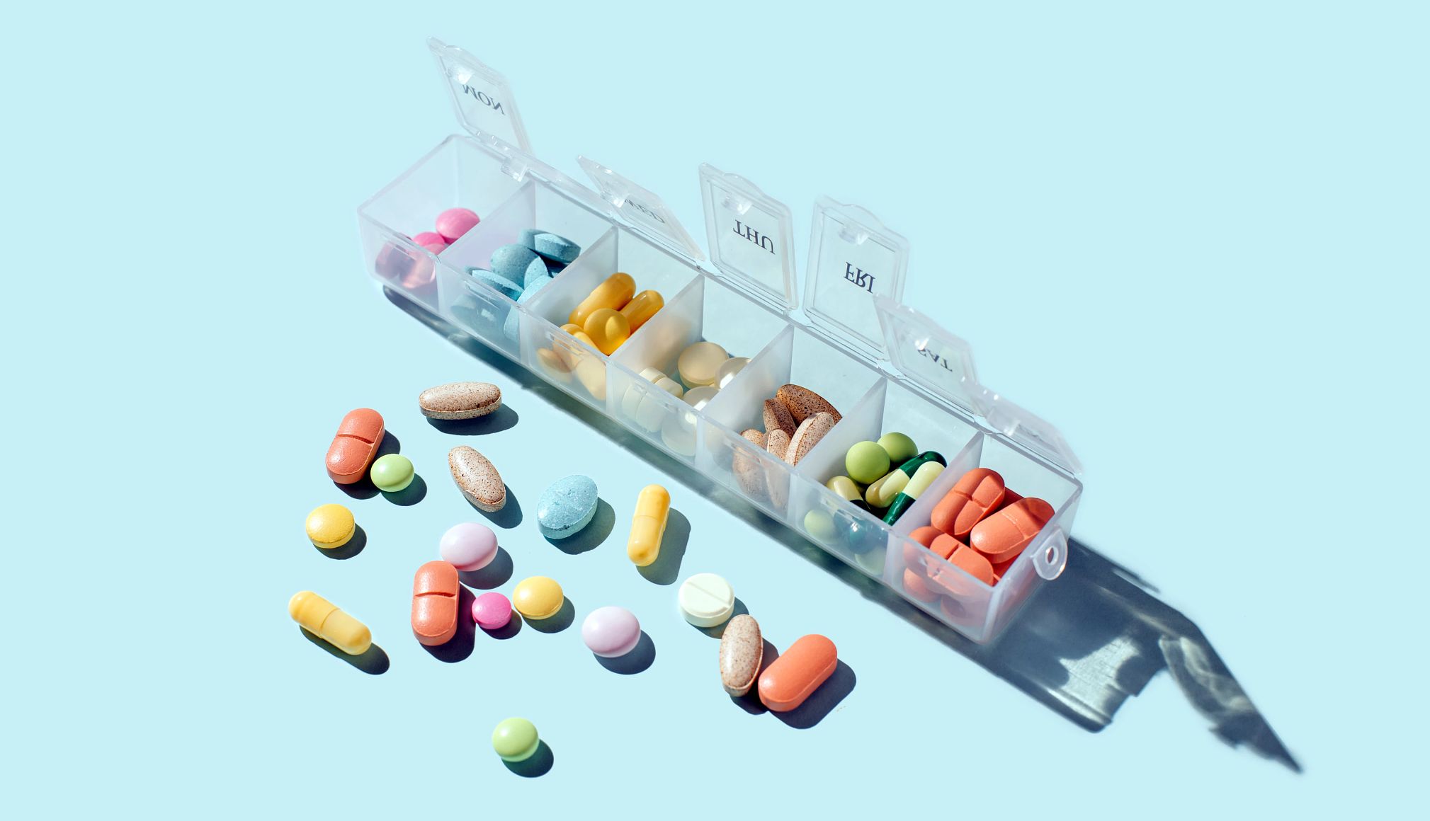 Medication Management Guide box filled with pills and capsules on blue background