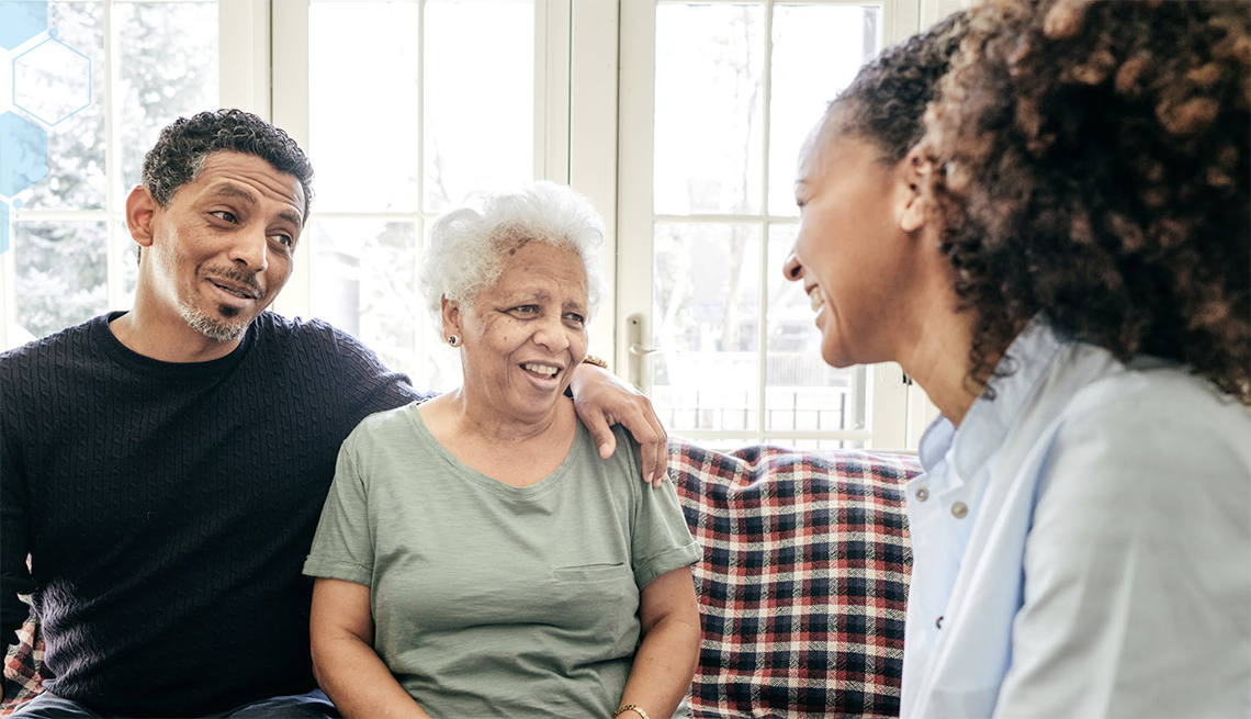 African Americans and Latinos face health and economic disparities in dementia A man and older woman sitting on a couch at home and talking to a female healthcare professional
