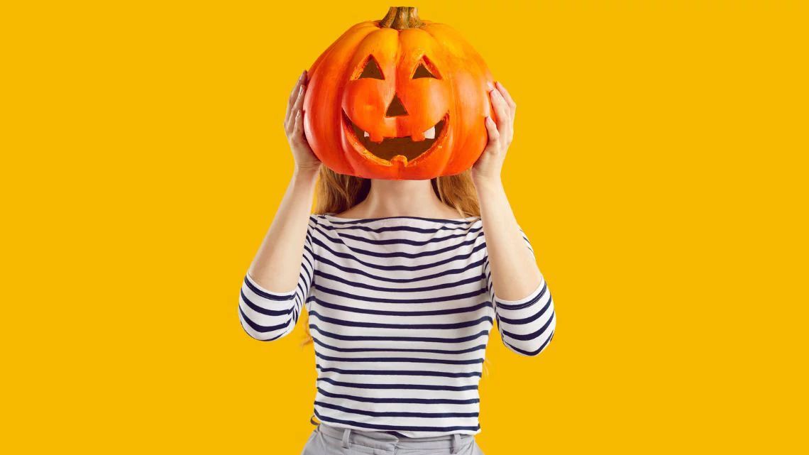 Woman holding a carved pumpkin.