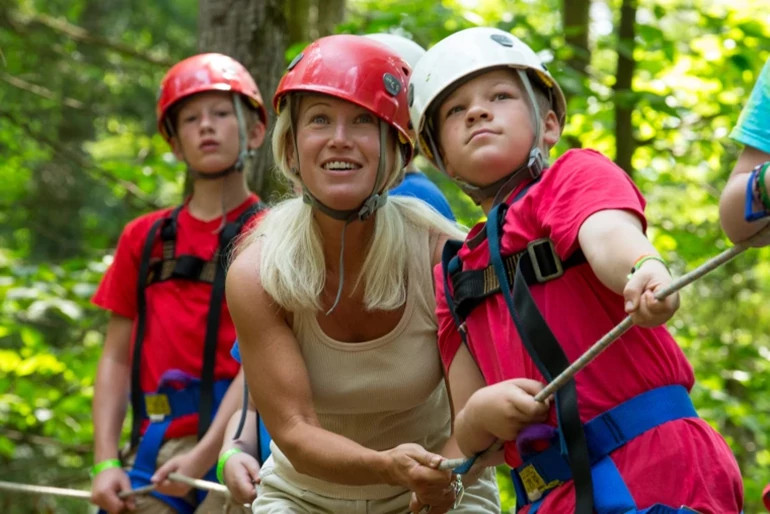 clean newman wearing a safety helmet with children on a ropes course