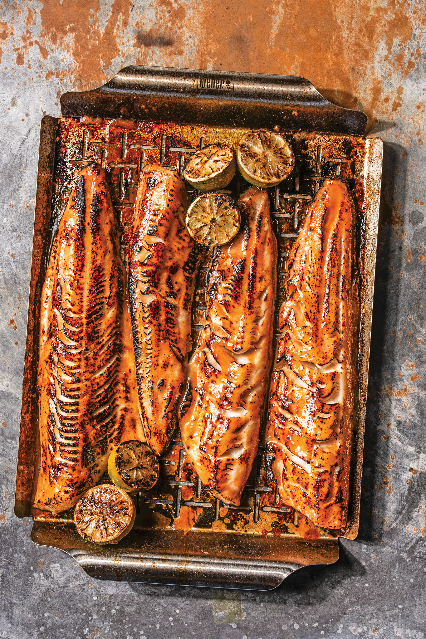 grilled black cod with grilled lime halves in a metal pan