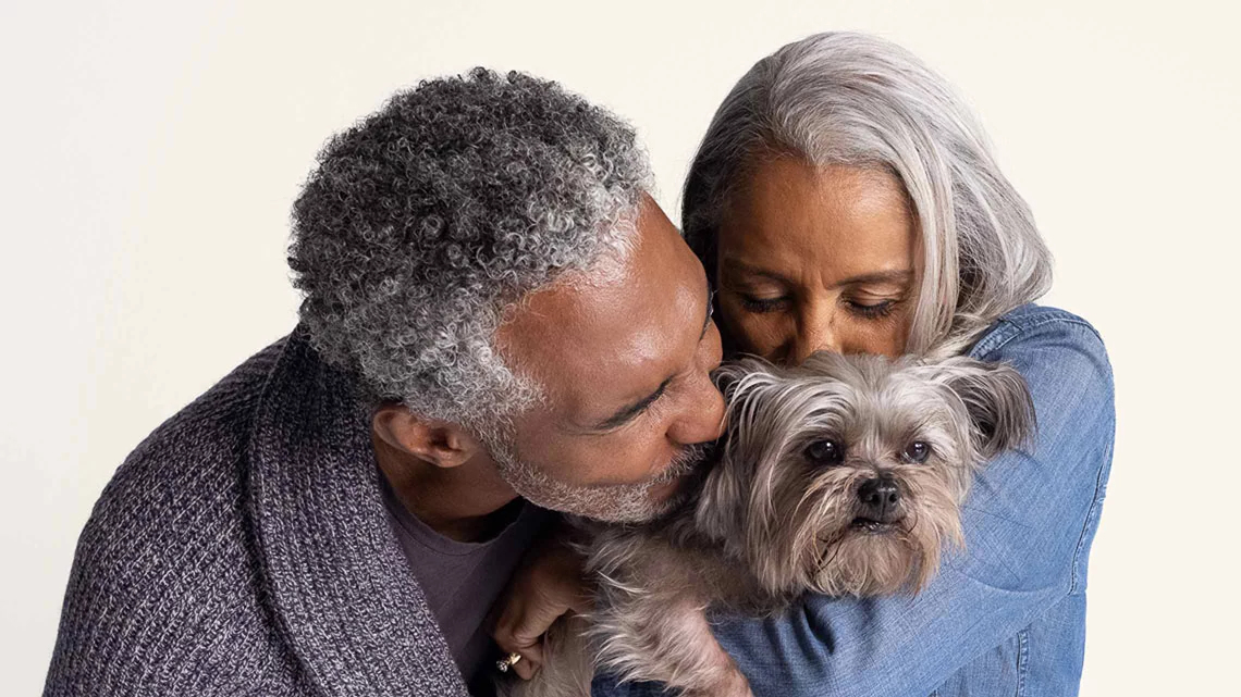 couple holding and kissing small dog