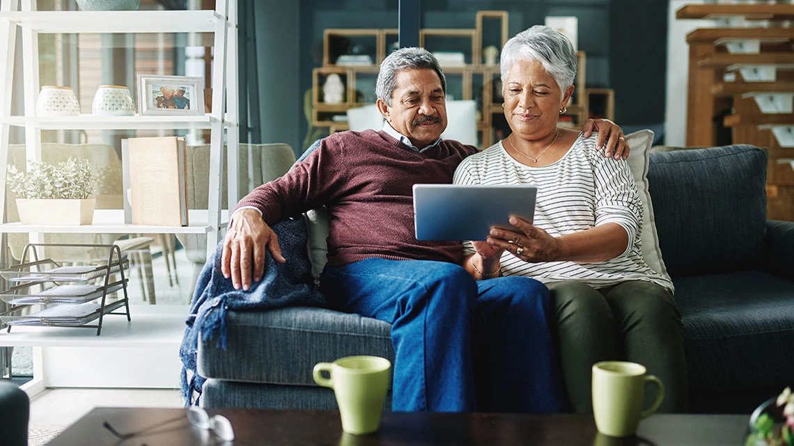 AARP Staying Sharp man and woman sitting on couch viewing a tablet