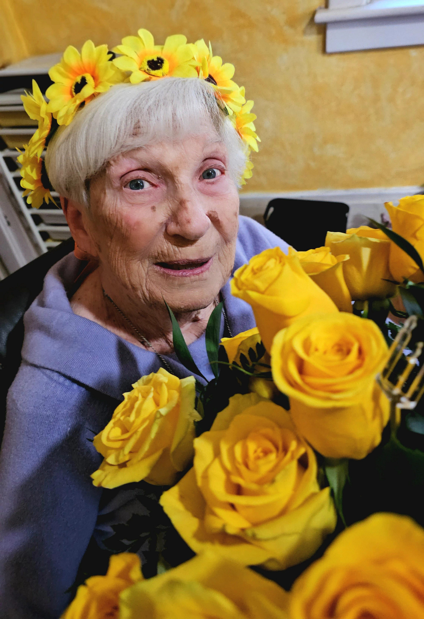 a photo shows author Lisa Suhay’s mother wearing a flower crown to greet children as part of Suhay’s Fairy Tree project in Norfolk, Virginia.