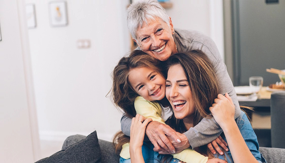 Grandmother, daughter and granddaughter hugging in living room