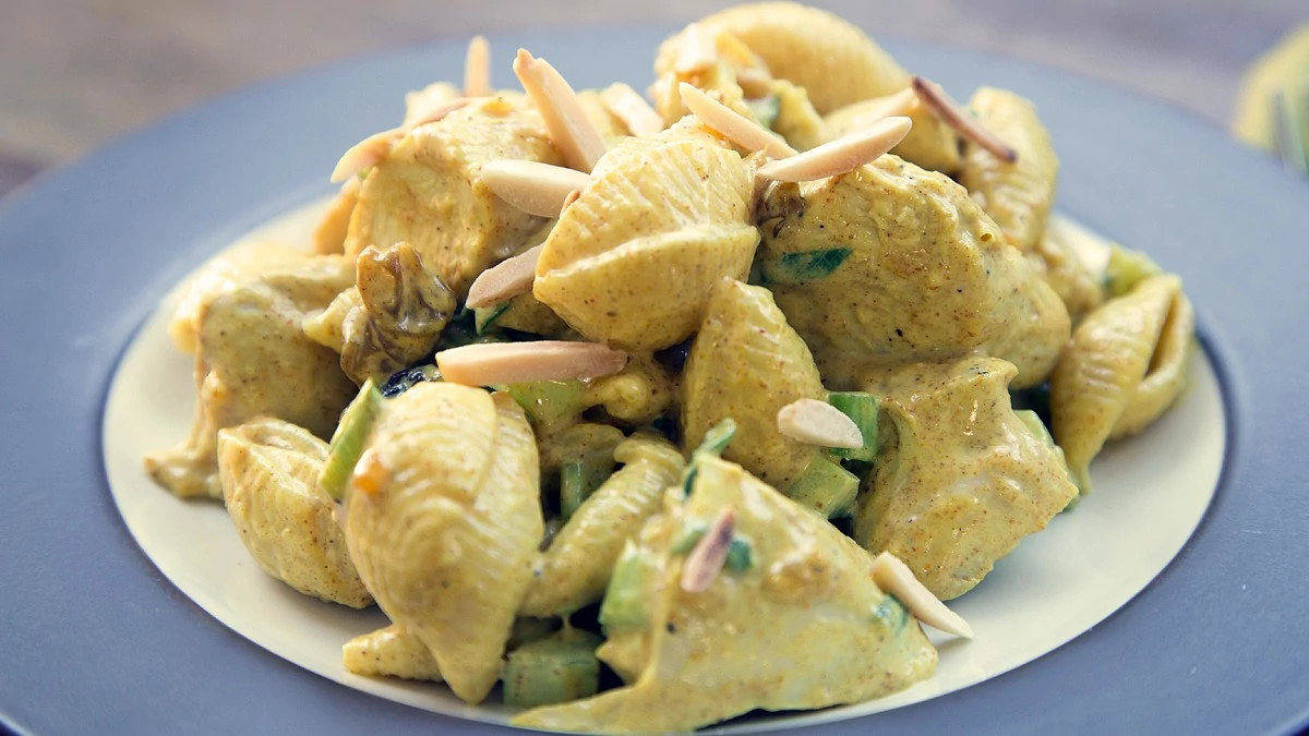 A close-up view of curried chicken and pasta salad on a plate