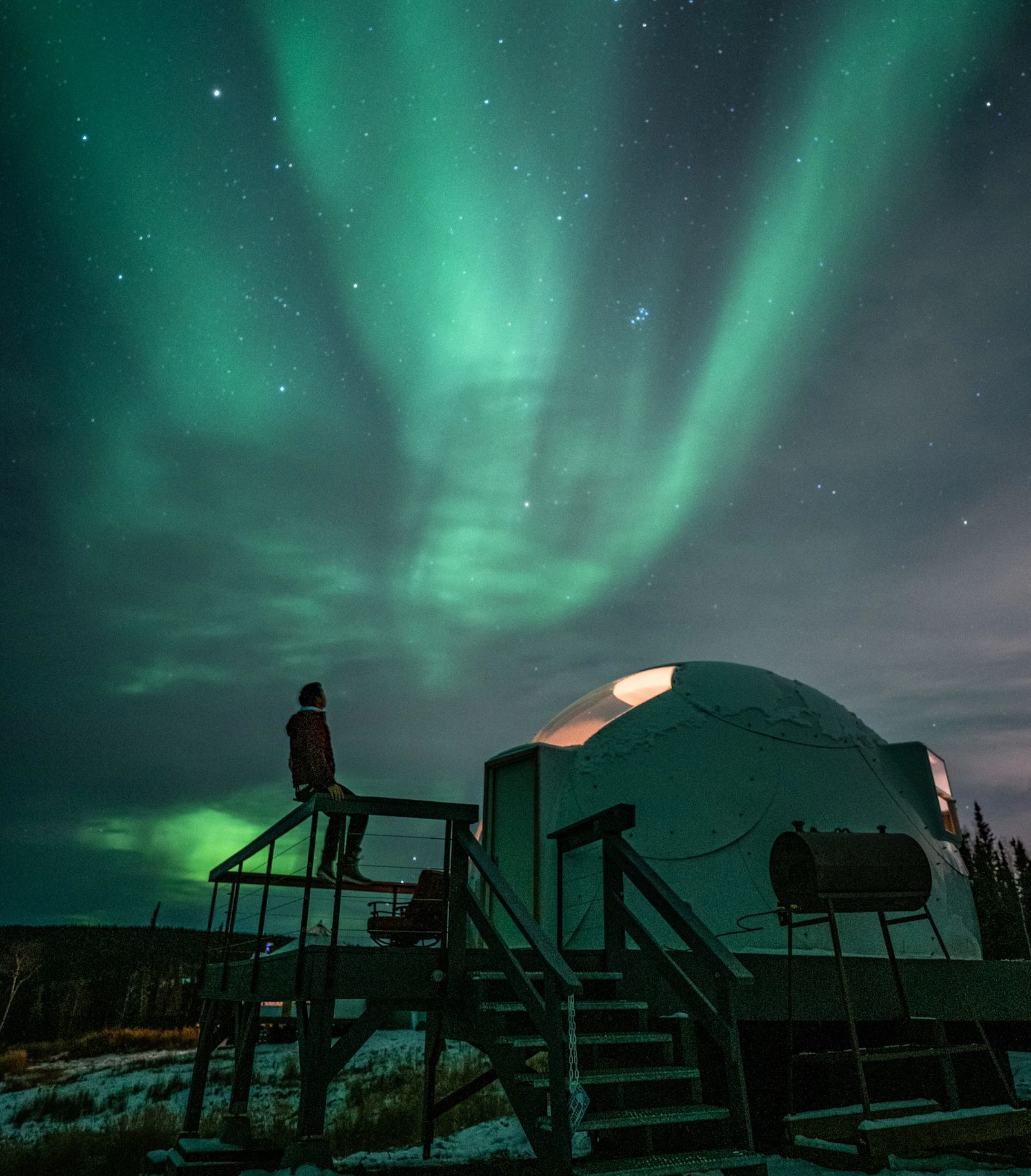 Un hombre mira el cielo iluminado con las auroras boreales.