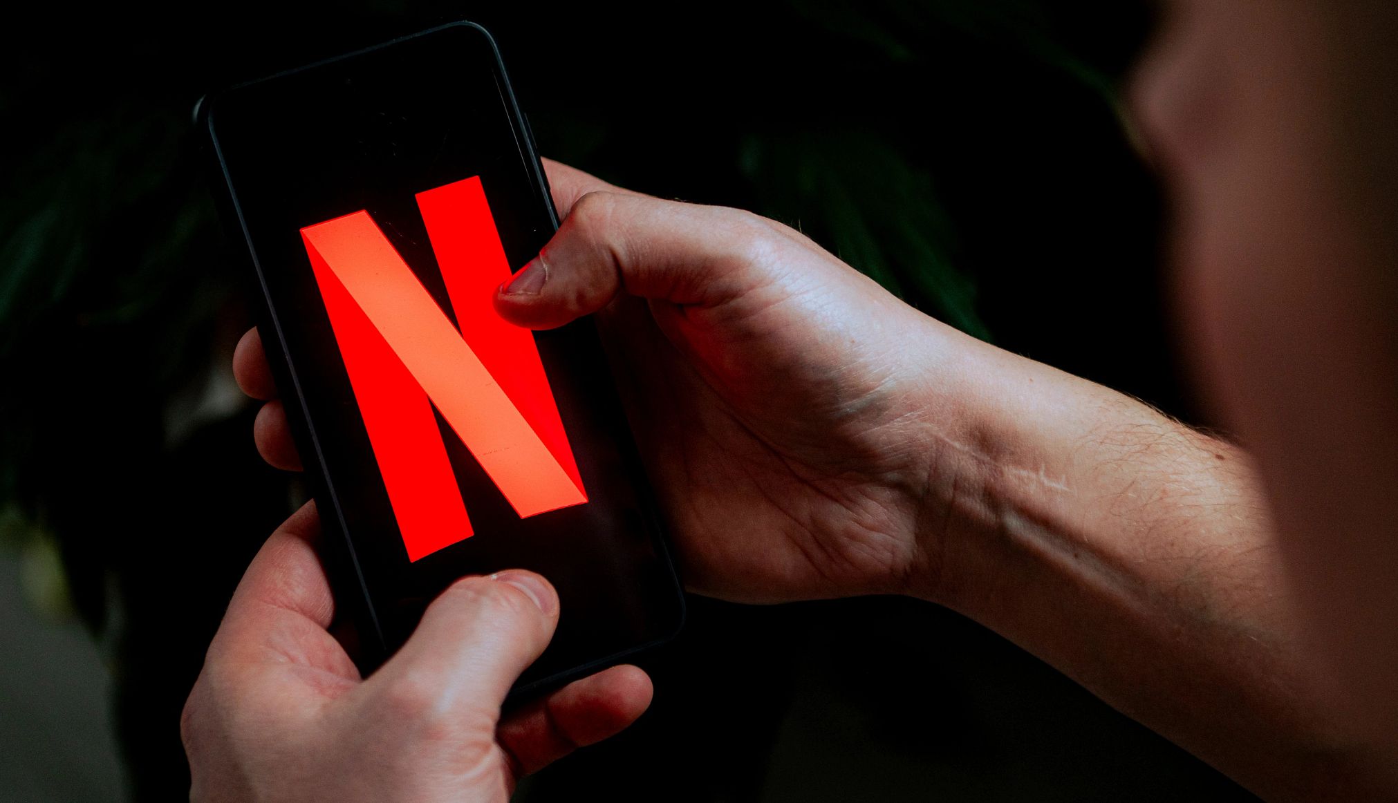 Netflix Ends Apple Billing Option A man opens the netflix app on his phone
