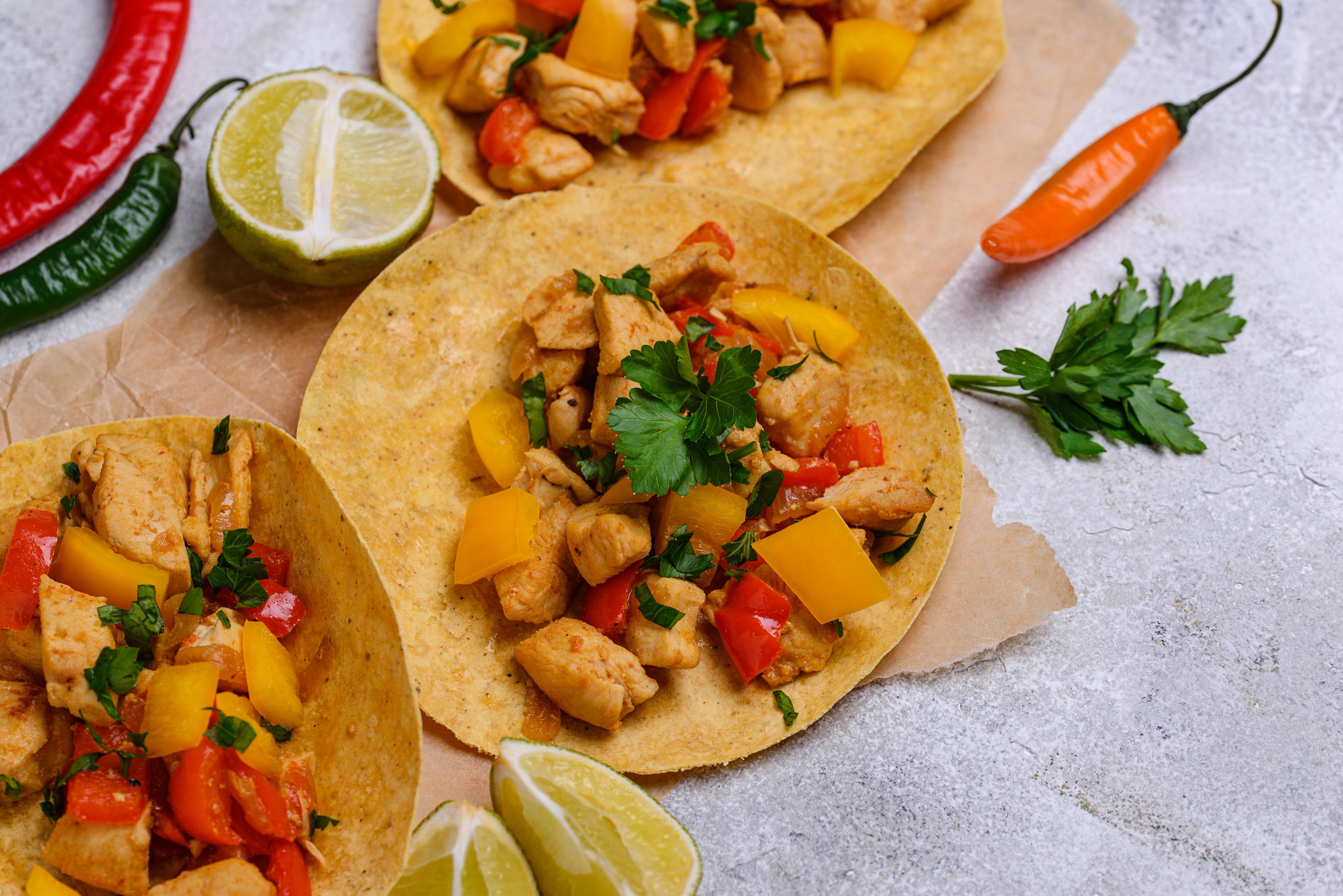 Tacos with chicken, cilantro, and bell peppers. Surrounded by limes and chiles.