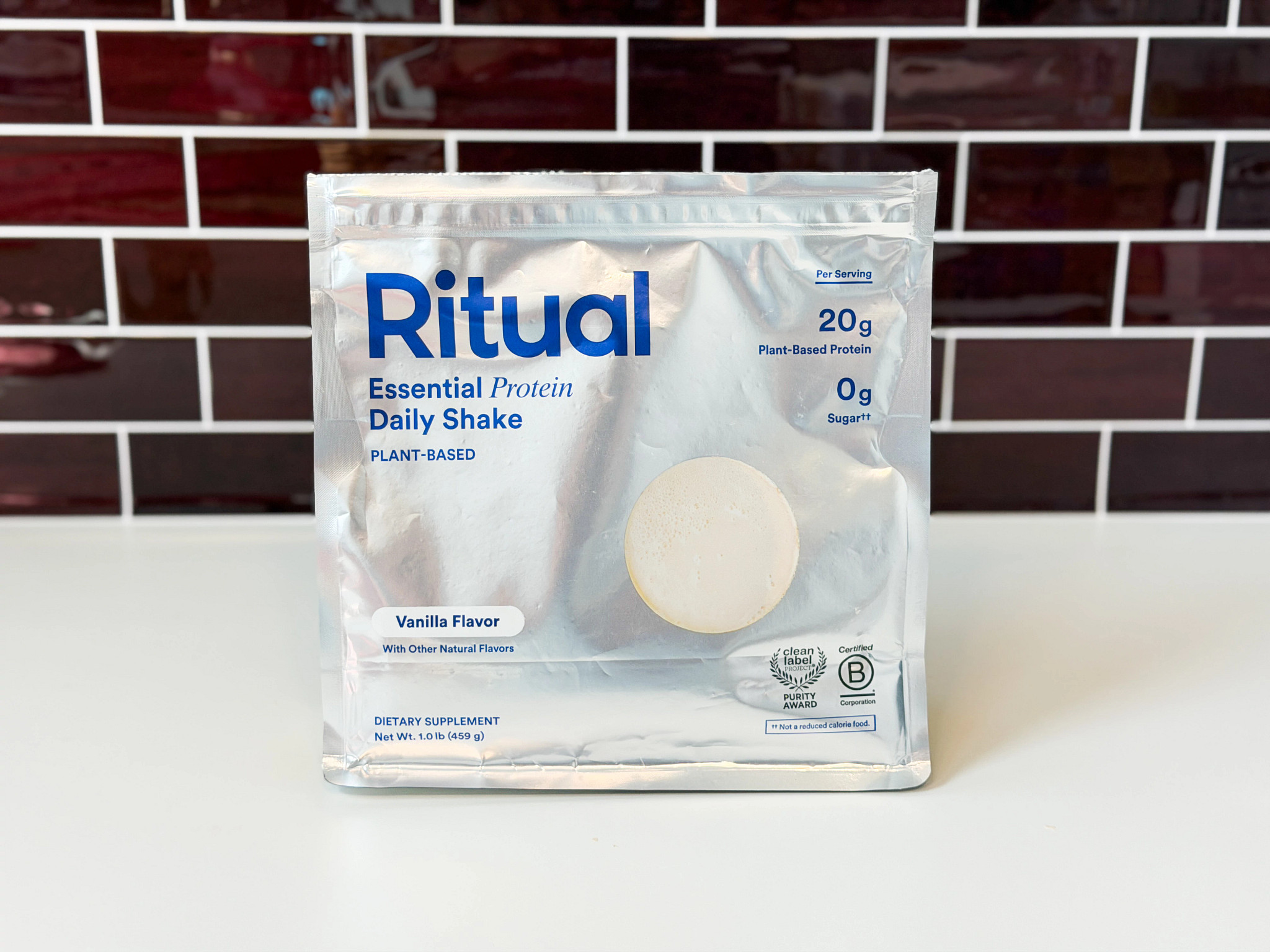 A bag of Ritual Essential Protein Daily Shake on a counter with a brick background