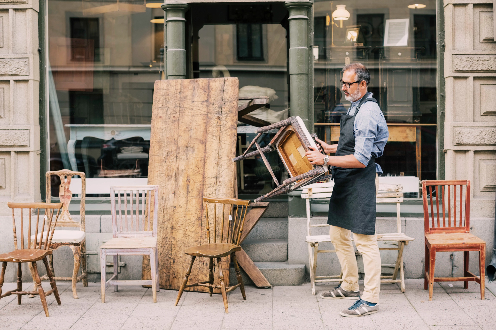 Man outside with a bunch of different chairs
