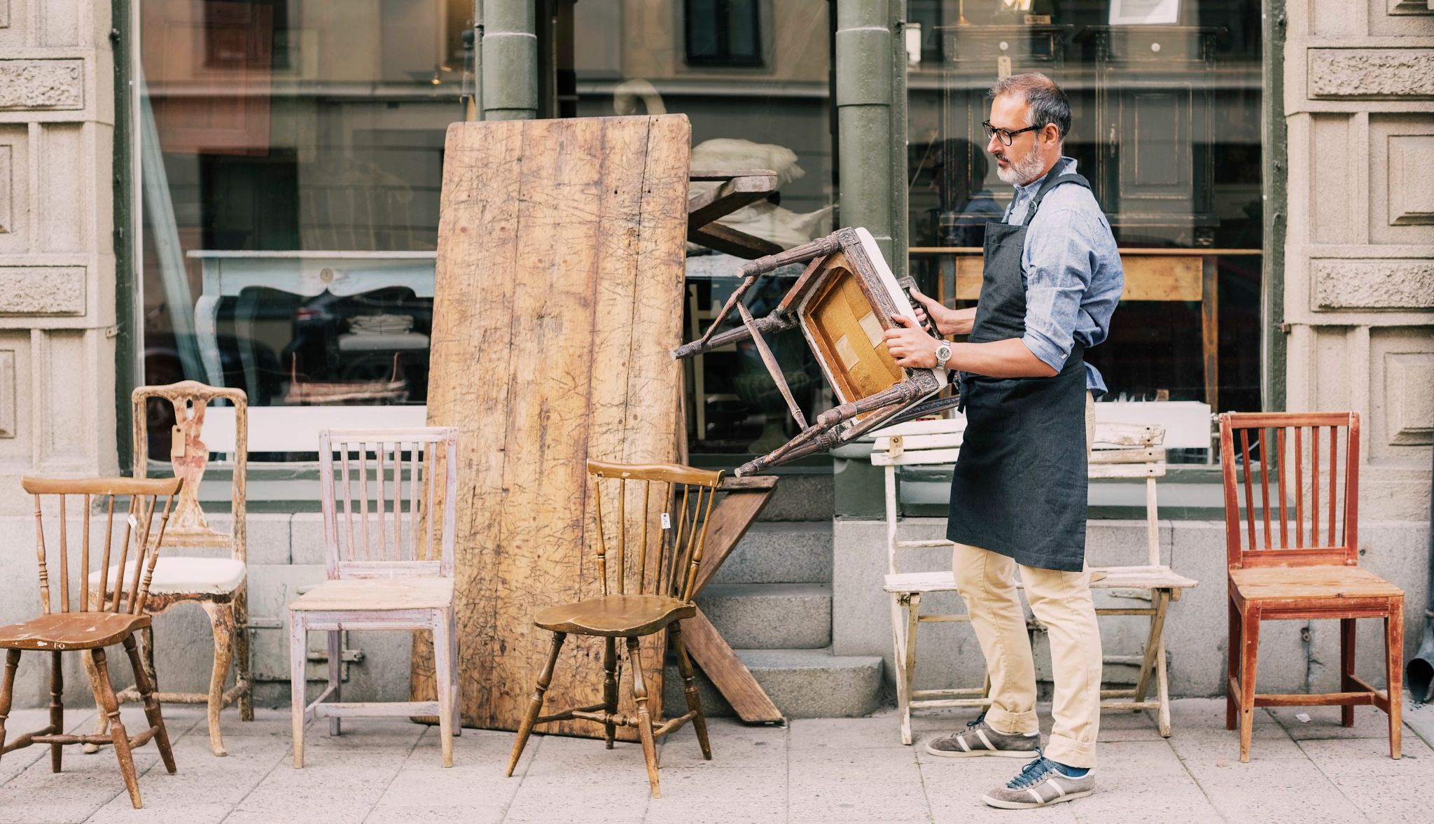 Reselling thrifted goods Man outside with a bunch of different chairs