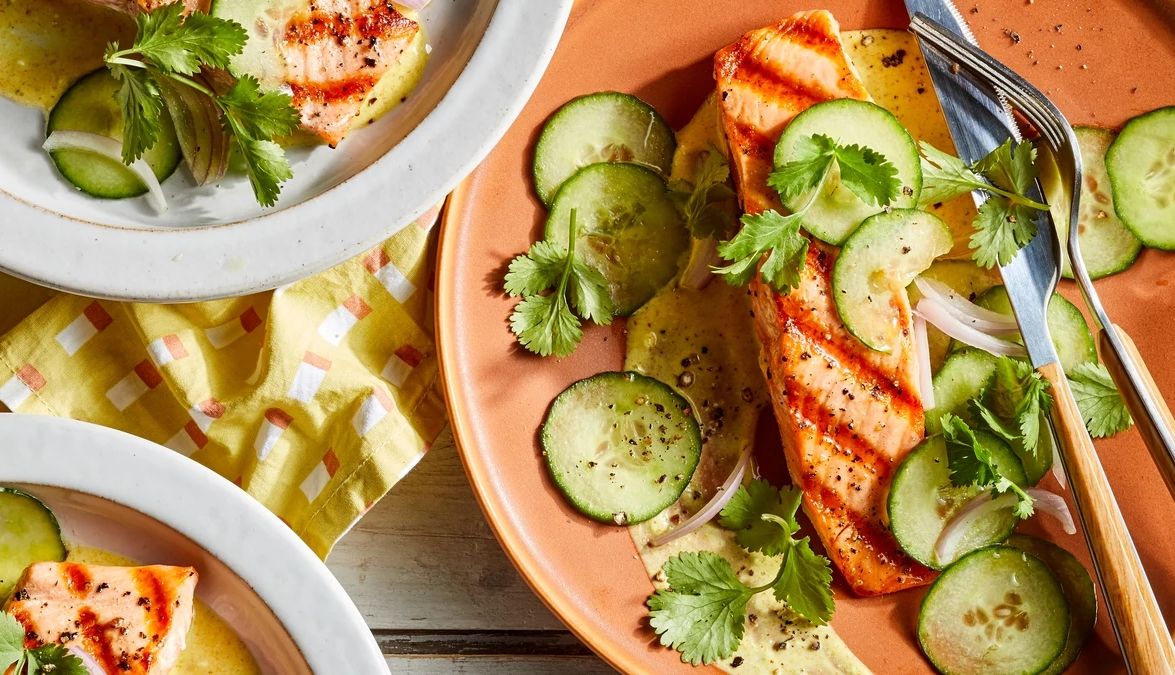 Salmon with curried yogurt and cucumber salad A close-up view of salmon with curried yogurt and cucumber salad on plates